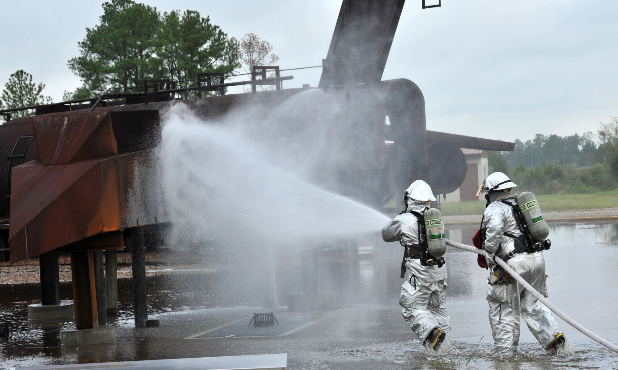 U.S Air Force Airman 1st Class Michael Costello, 633rd Civil Engineer Squadron firefighter, and Antonio Ortiz, 633rd Civil Engineer Squadron lead firefighter, extinguish a fire during a major accident response exercise at Langley Air Force Base, Va., Sept. 22, 2011. The exercise tested and evaluated the responses to multifaceted events affecting the installation to include search and rescue, aircraft crash, hydrazine leak, nuclear munitions, mass casualty, and safety investigation scenarios. (U.S. Air Force photo by Airman 1st Camilla Griffin/Released)