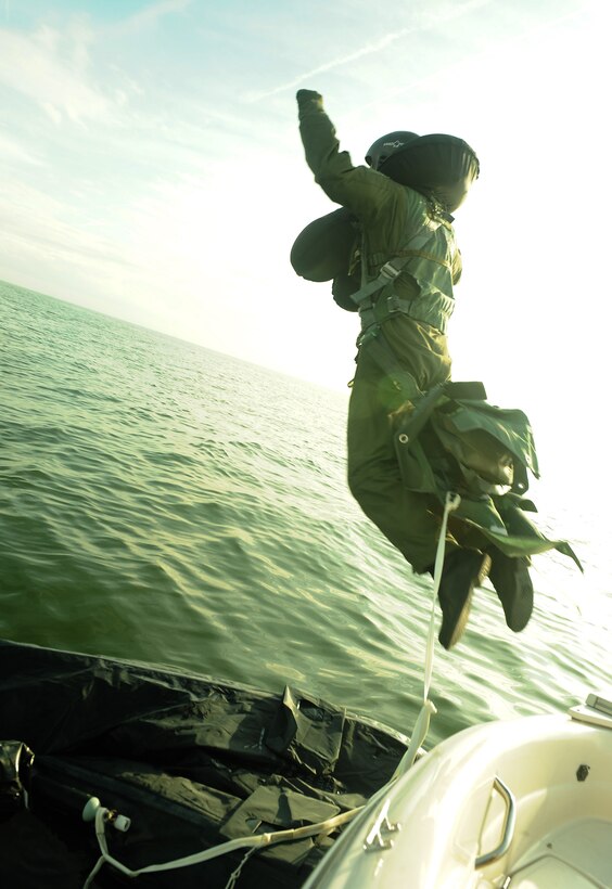 A uniformed man jumping into open water.