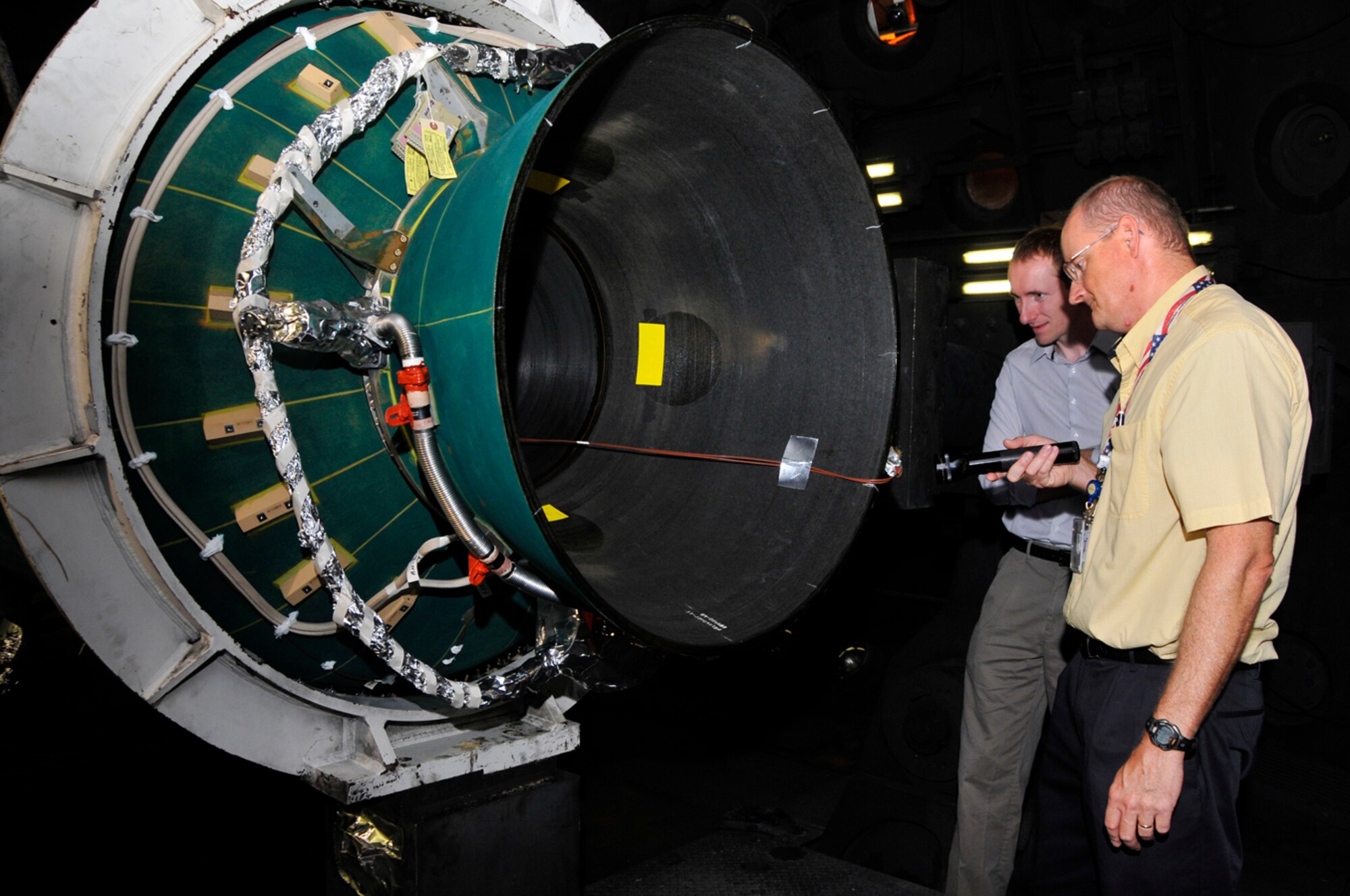 From left to right, Brad Wichtoski and Scott Gibbons with Northrop Grumman, conduct an inspection of a Minuteman III Stage 3 motor before it undergoes simulated altitude testing in AEDC’s J-6 Large Rocket Test Facility. (Photo by Rick Goodfriend)