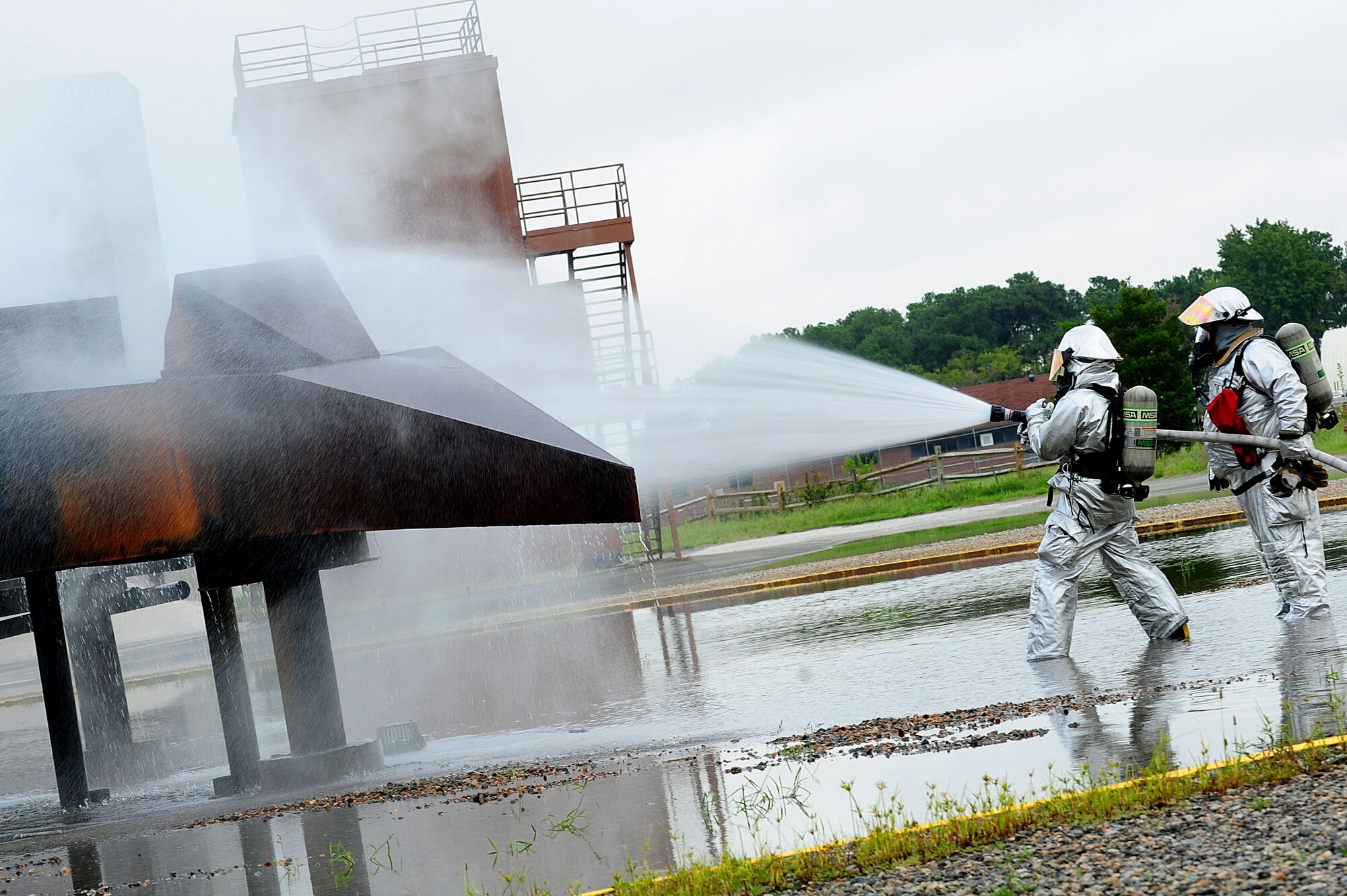 U.S. Air Force Airman 1st Class Michael Costello, 633rd Air Base Wing Civil Engineer Squadron fire fighter, and Antonio Ortiz, 633rd ABW CES lead fire fighter, extinguish flames from a simulated aircraft during a major accident response exercise at Langley Air Force Base, Va., Sept. 22, 2011.  The exercise was held to test and evaluate the responses to multifaceted events affecting the installation. (U.S. Air Force photo by Airman 1st Class Kayla Newman/Released)