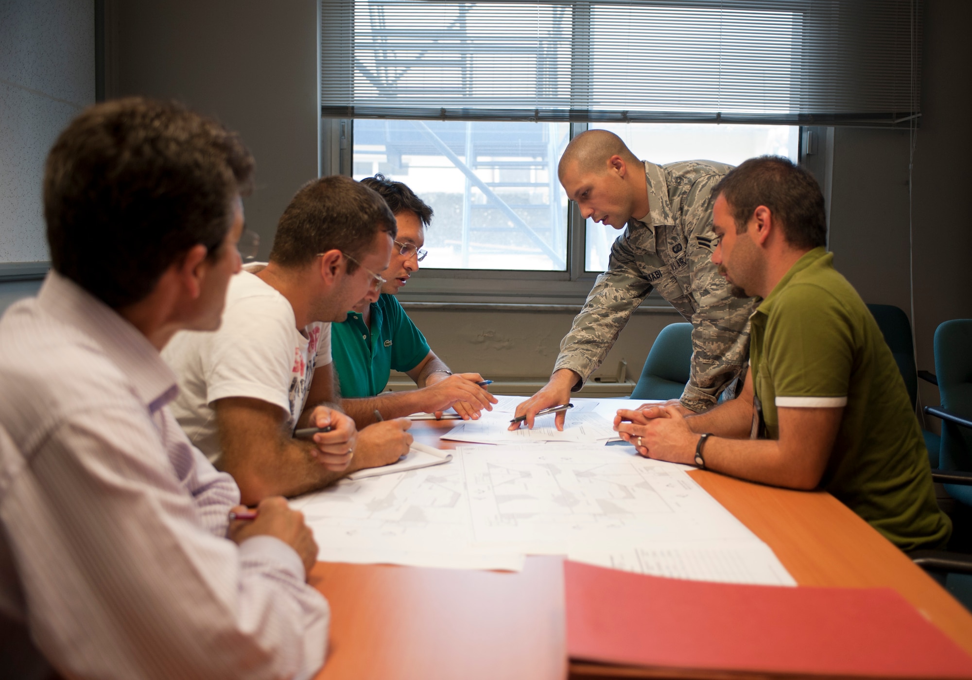 Airman 1st Class Eric Punjabi, 39th Contracting Squadron contract administrator, reviews a project package with contractors and technical experts Sept. 22, 2011, at Incirlik Air Base, Turkey. The contracting squadron's primary mission is divided into the services and commodities flight and infrastructure flight. The flights prepare project packages for every contract on base. (U.S. Air Force photo by Senior Airman Clayton Lenhardt/Released)