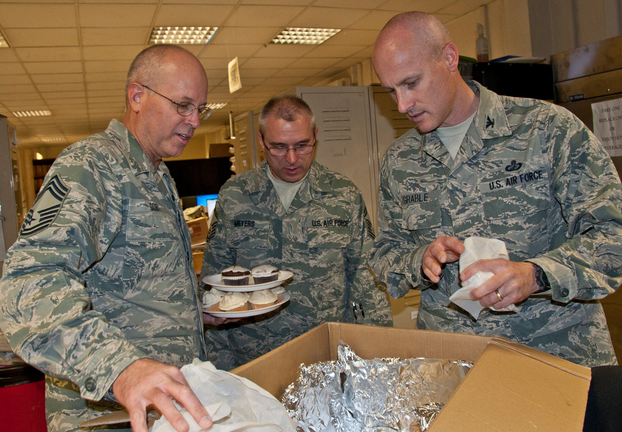 KANDAHAR AIRFIELD, Afghanistan -- Chief Master Sgt. Glenn Doby (left) and Col. Samuel Grable (right) shows Senior Master Sgt. Martin Meyers, 451st Expeditionary Logistics Readiness Squadron aerial port flight, the cupcakes and cookies for the aerial port Airmen. Grable and Doby, 451st Expeditionary Mission Support Group, handed out cupcakes and cookies to members of the 451st Air Expeditionary Wing who could not attend the Air Force Birthday Bash at Camp Losano. Grable and Doby visited nine units and wished them a happy Air Force birthday. (U.S. Air Force photo by Senior Airman David Carbajal)