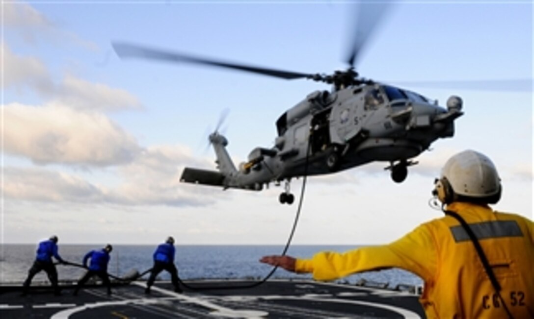Petty Officer 2nd Class Alexander Black signals the pilot of an MH-60 Sea Hawk during an in-flight refueling from the guided-missile cruiser USS Bunker Hill (CG 52) as the ship operates in the Pacific Ocean on Sept. 10, 2011.  Bunker Hill is conducting a three-week composite training unit exercise in preparation for a deployment to the western Pacific Ocean.  The Sea Hawk is assigned to Helicopter Combat Squadron 23.  DoD photo by Seaman John Grandin, U.S. Navy.  