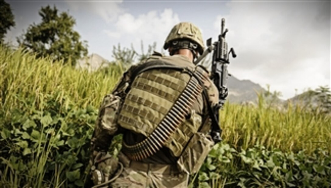 U.S. Army Spc. Jake Amato, an MK48 machine gunner assigned to Laghman Provincial Reconstruction Team, patrols through a field looking for triggermen in the Alisheng district, Laghman province, Afghanistan, on Sept. 12, 2011.  