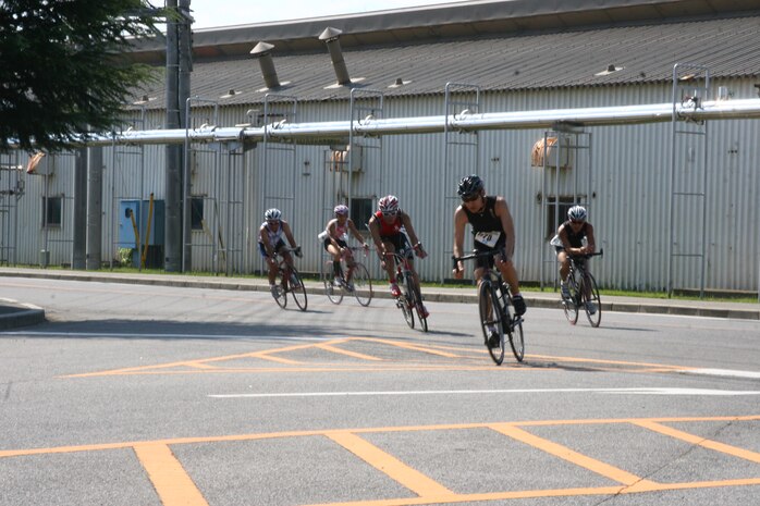 Kenichi Kabe, a confident cyclist, leads a pack of competitors through a turn on their third lap of a four lap bicycle portion of the Marine Corps Community Services Iwakuni Modified Triathlon here Sunday. During a triathlon, competitors race their customized lightweight bicycles 32 kilometers right before a foot race to the finish line. 200 participants came out fight their way through a 1 kilometer swim, 32K bike ride and two 4K runs.