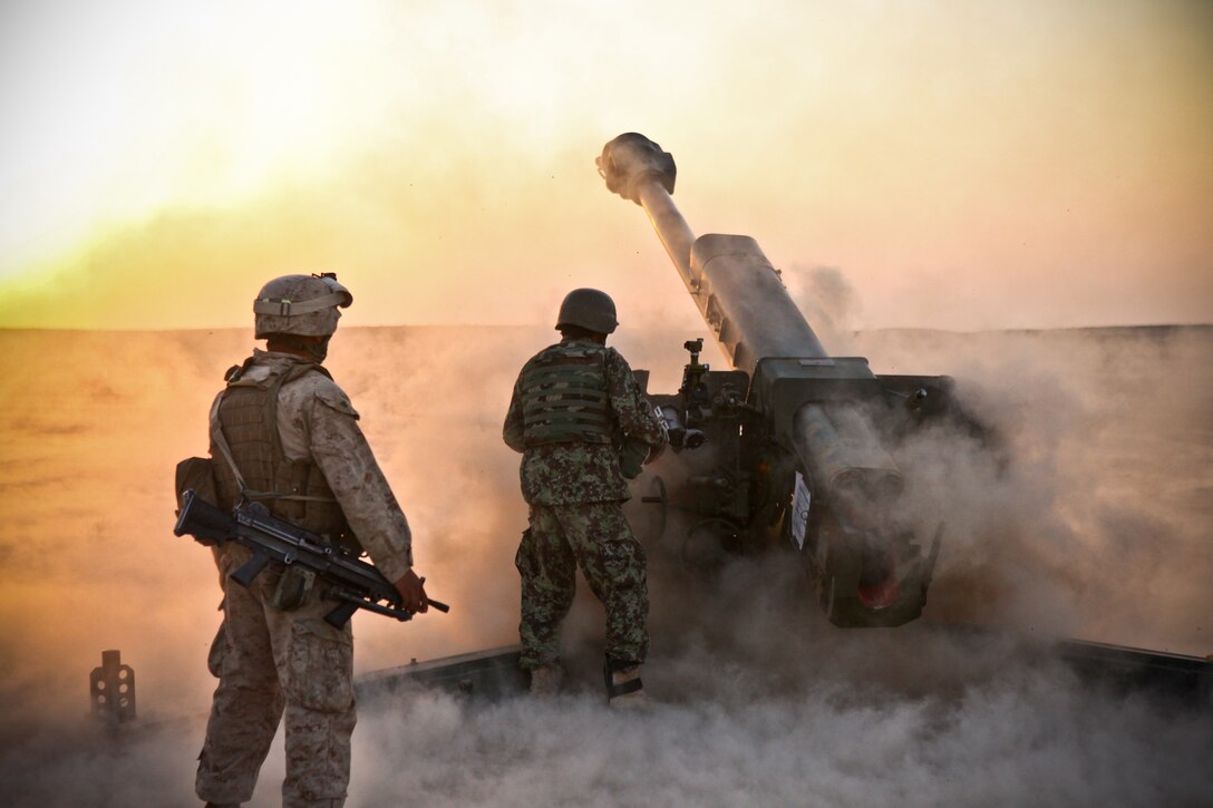 Manassas, Va., native Cpl. Alonso Arviso (left), an assistant section chief with Charlie Battery, 1st Battalion, 12th Marine Regiment, observes an Afghan National Army soldier with 4th Kandak, 1st Brigade, 215th Corps as he fires rounds down range.  The Afghan soldiers spent three days in the desert working with the 122 mm howitzer D-30 artillery cannons to increase the soldiers’ confidence with the weapon system.