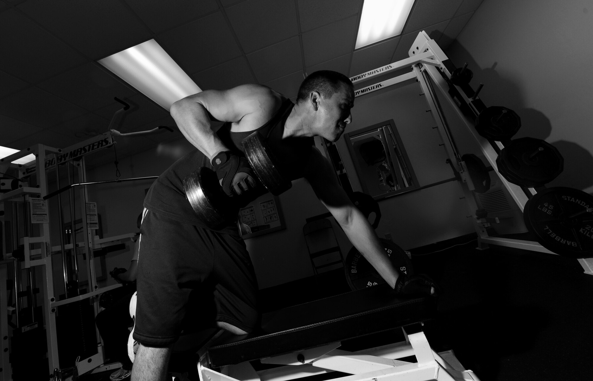 Senior Airman Sean Murphy, 18th Civil Engineer Squadron fireman, performs a dumbell row during a workout at Fire Station 1, here on Kadena Air Base, Japan, Sept. 21. Murphy and the other firemen spend their downtime by performing cardiovascular and weight-training exercises in order to maintain fitness.(U.S. Air Force photo/Airman 1st Class Jarvie Z. Wallace)
 