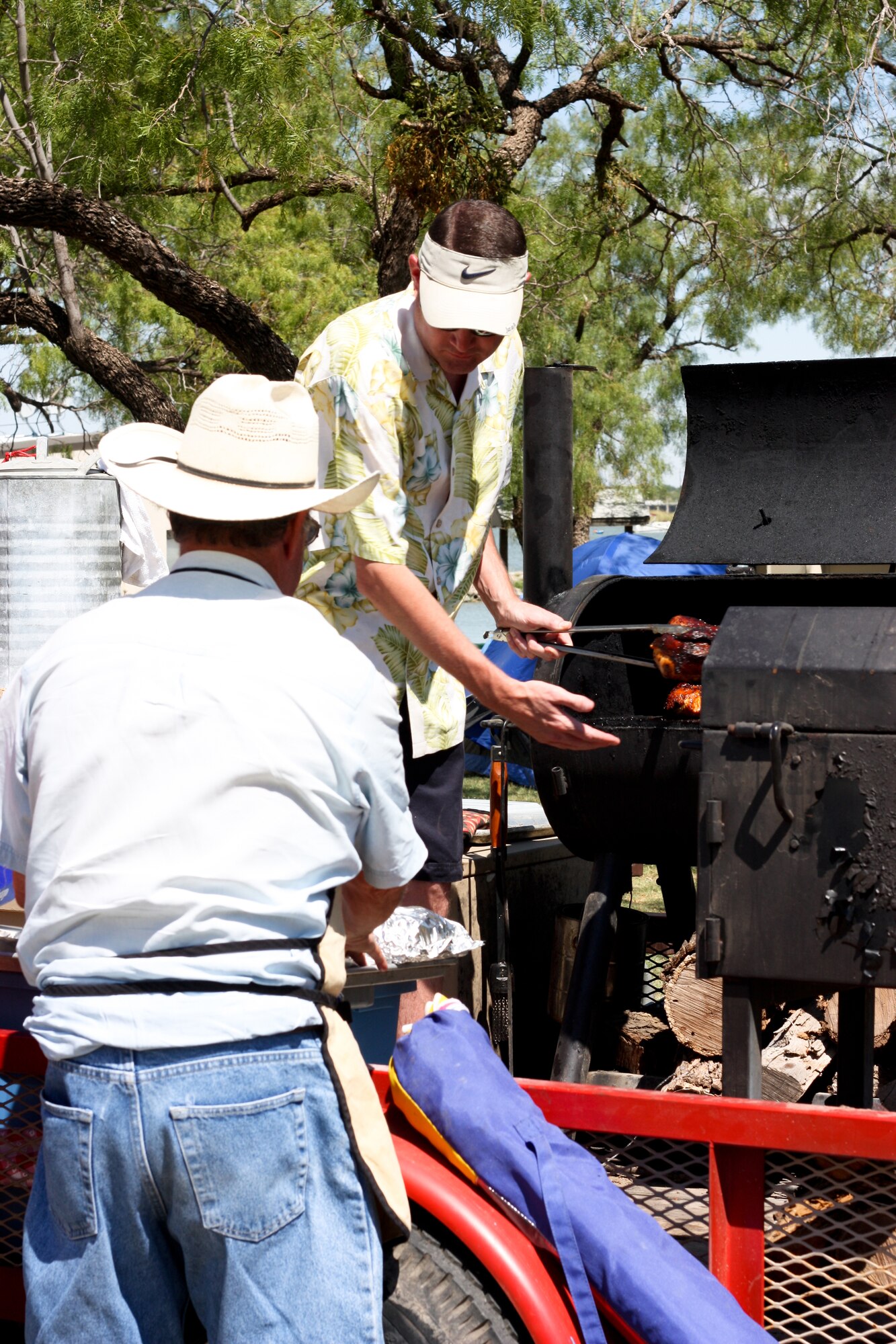 SAN ANGELO, Texas -- Marty Penell works the grill while his father, Johnny Penell prepares the chicken during the 38th Annual Armed Forces Chili Cookoff at the Recreation Camp Sept. 24. Along with Vickie Pennell, Marty's mother and Johnny's wife, they group called themselves the Hooking Bull team. This was the team's sixth year participating in the cookoff, with four trophies under their belt. This year they entered in each competition: Ribs, Chicken, Baked Beans and Chili. (Courtesy photo/Whitney Haskell)