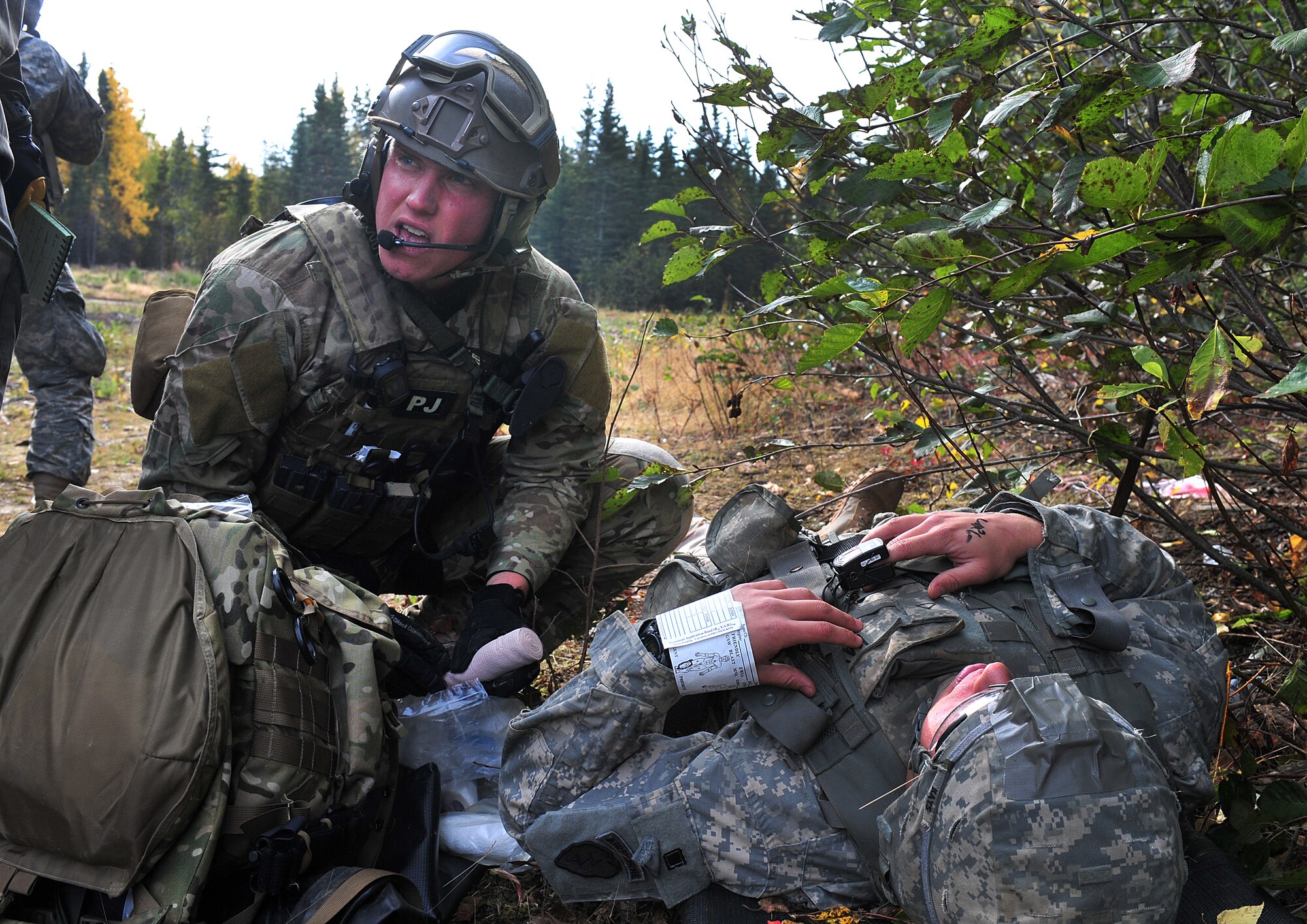 Staff Sgt. BIll Cenna, 212th Rescue Squadron pararescueman, looks for more information on the patient he's working on during a training scenario at Joint Base Elmendorf-Richardson on September 21, 2011.  The training scenario focused on quick-care-under-fire and also gave training to Baker Company, 3rd Battalion (Airborne), 509th Infantry Regiment, on how to react when pararescuemen arrive.  (U.S. Air Force photo/Staff Sgt. Zachary Wolf)