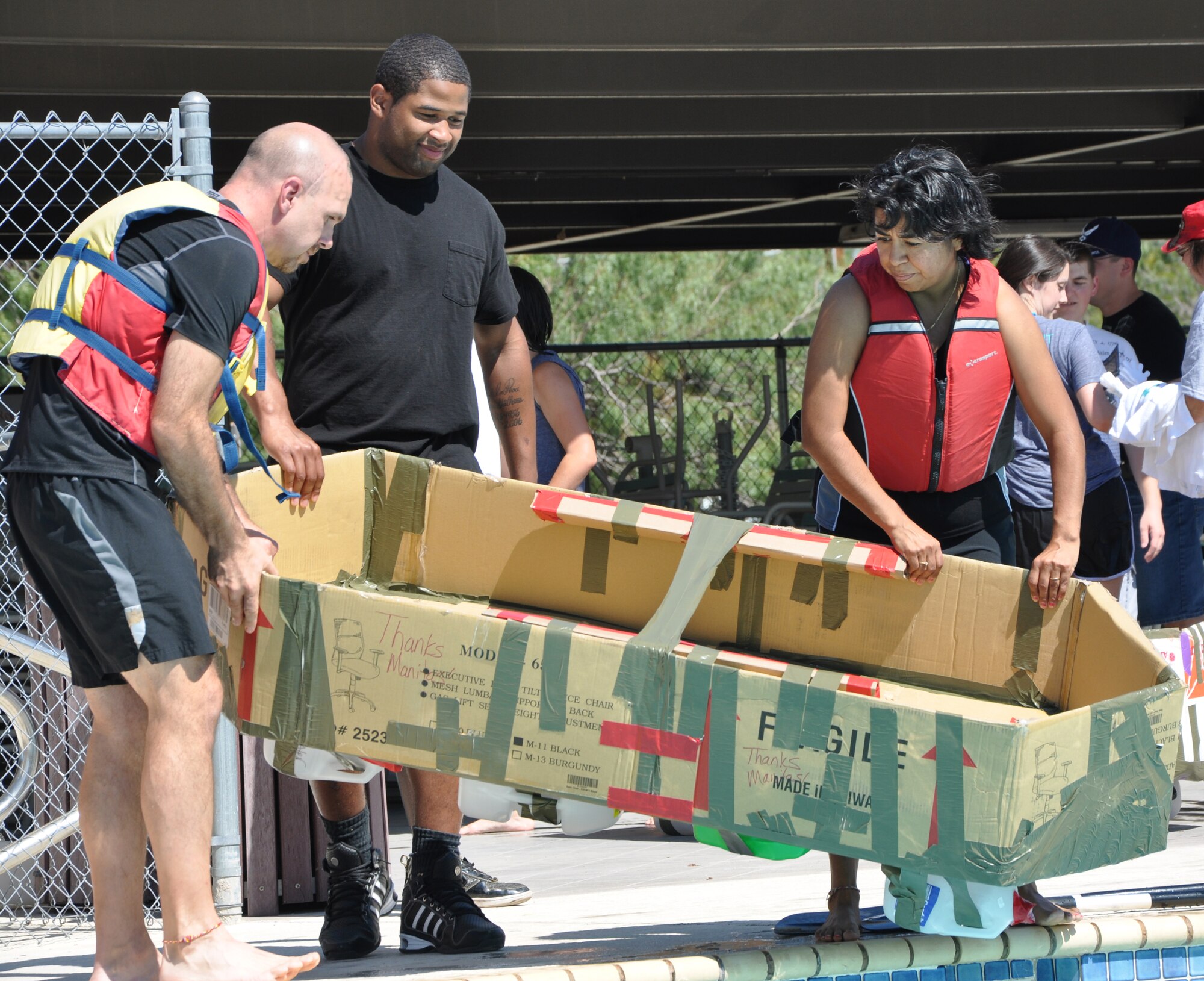 SAN ANGELO, Texas -- (From left:) Kelly Dunn, Airman 1st Class Clifton Gathers, 17th Comptroller Squadron, and Mary Dunn, 17 CPTS, launch their boat made of cardboard boxes, duct tape and milk jugs into the Recreation Camp pool during the Build a Boat contest Sept. 24. (U.S. Air Force photo/Connie Hempel)  