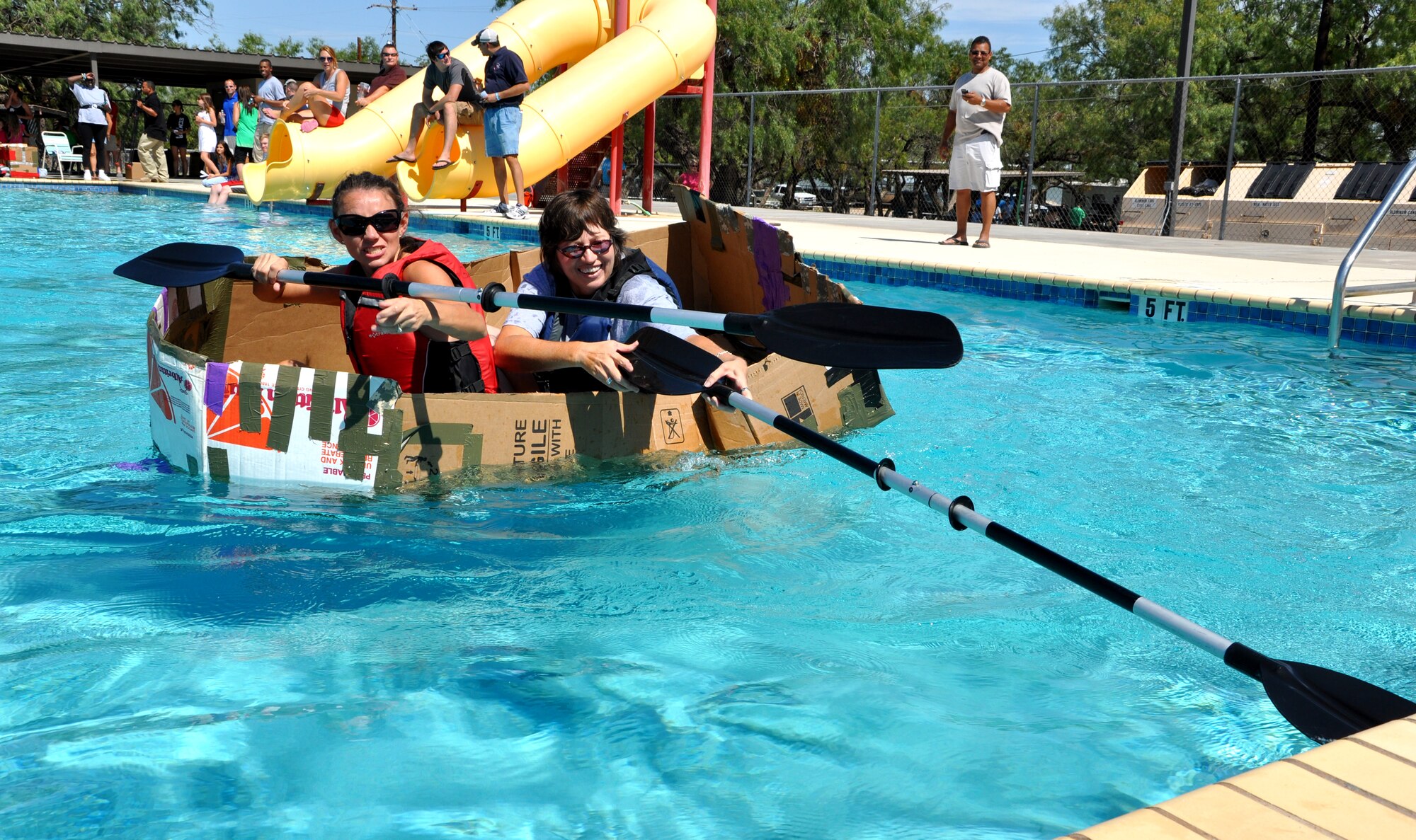 SAN ANGELO, Texas -- Donna Casey and Lori Matus, both from the Sexual Assault and Response office, reach for the midway point before heading back to the finish line in their boat made of boxes, duct tape and milk jugs during the Build a Boat contest at the Recreation Camp Sept. 24. (U.S. Air Force photo/Connie Hempel)