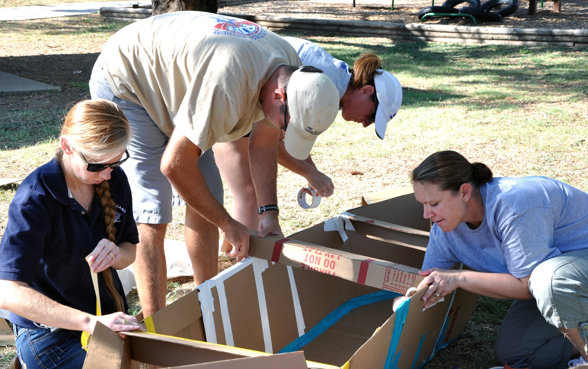 SAN ANGELO, Texas -- Team Puppies and Ponies work on their makeshift boat of cardboard, duct tape and milk jugs during the Build a Boat contest at the Recreation Camp Sept. 24.  Their final product won The Fastest Boat category against five other teams during the event. (U.S. Air Force photo/Connie Hempel)
