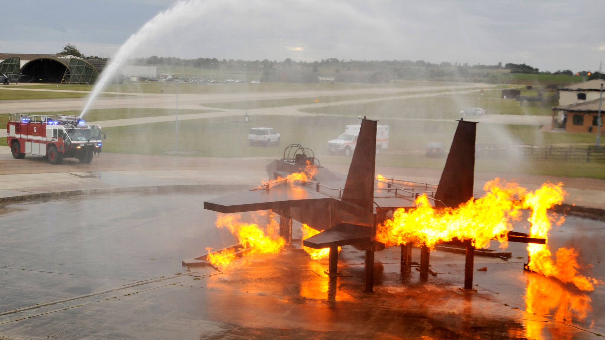 ROYAL AIR FORCE LAKENHEATH, England - Firefighters from the 48th Civil Engineer Squadron and Col. Scott Benza, 48th Mission Support Group commander, extinguish a mock F-15 fire from a fire truck during a live fire training demonstration on Sept. 22, 2011. Benza along with Lt. Col. Michael Zrostlik, 48th MSG deputy commander, visited the 48th CES firefighters to experience their training. The commanders donned full fire safety equipment, extinguished mock structural fires through newly learned extinguishing techniques and controlled the fire fighting system in the fire trucks as they circled around a mock F-15 fire. (U.S. Air Force photo by Senior Airman Tiffany M. Deuel)