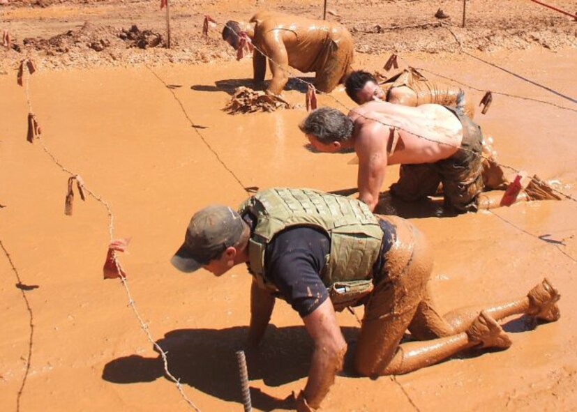 Participants crawl in the mud under strands of treacherous barbed wire during the Warrior Dash event held Aug. 28, 2011 in Huntersville, N.C.  Two reservists from the 916th Air Refueling Wing here battled Hurricane Irene on their drive west to compete in the run. (USAF courtesy photo)