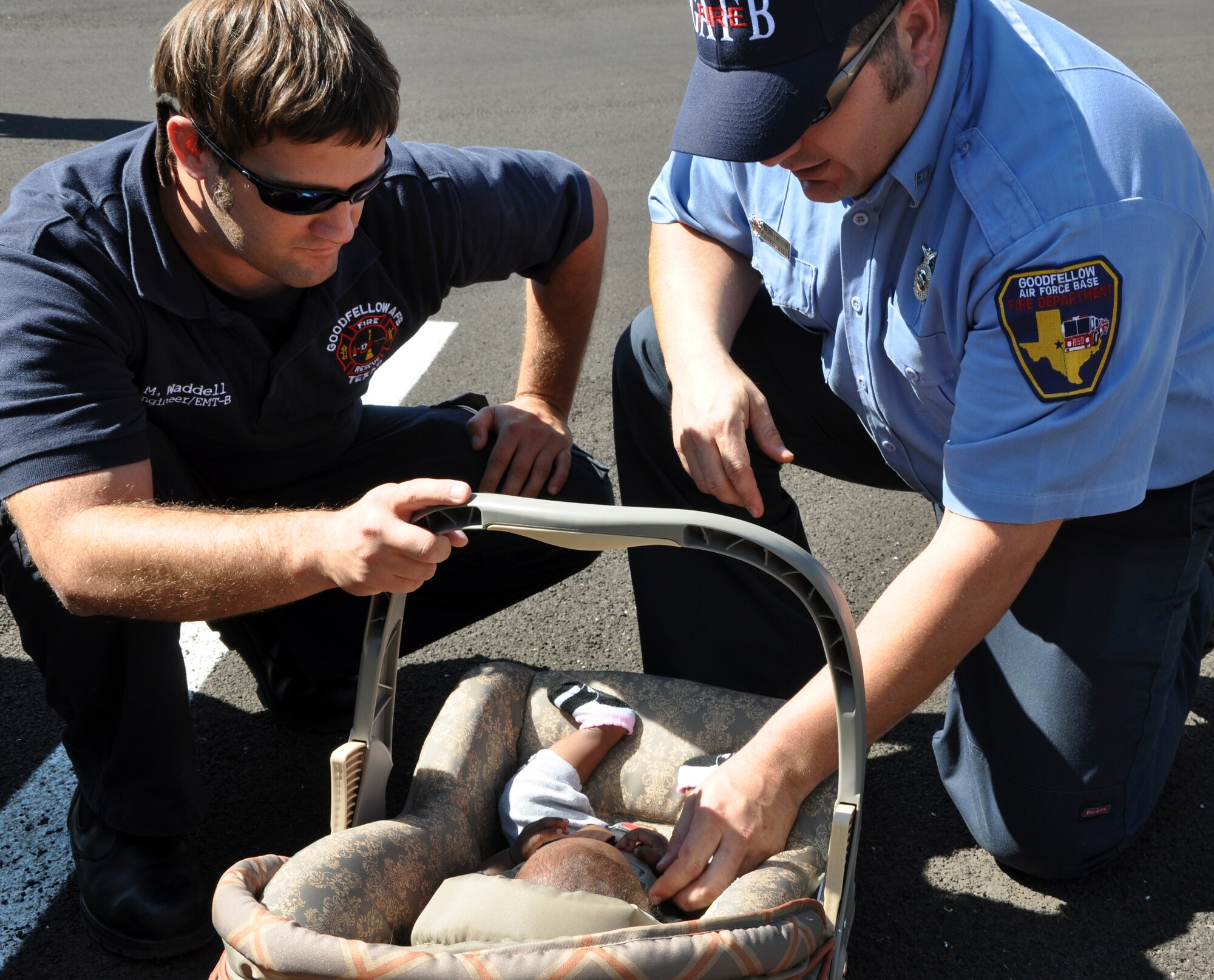 GOODFELLOW AIR FORCE BASE, Texas -- (From left:) Goodfellow firefighters Michael Waddell and Kevin Frierson check for the appropriate tightness and buckle location of a child restraint during the child safety seat check Sept. 23 at the commissary parking lot. (U.S. Air Force photo/Connie Hempel)