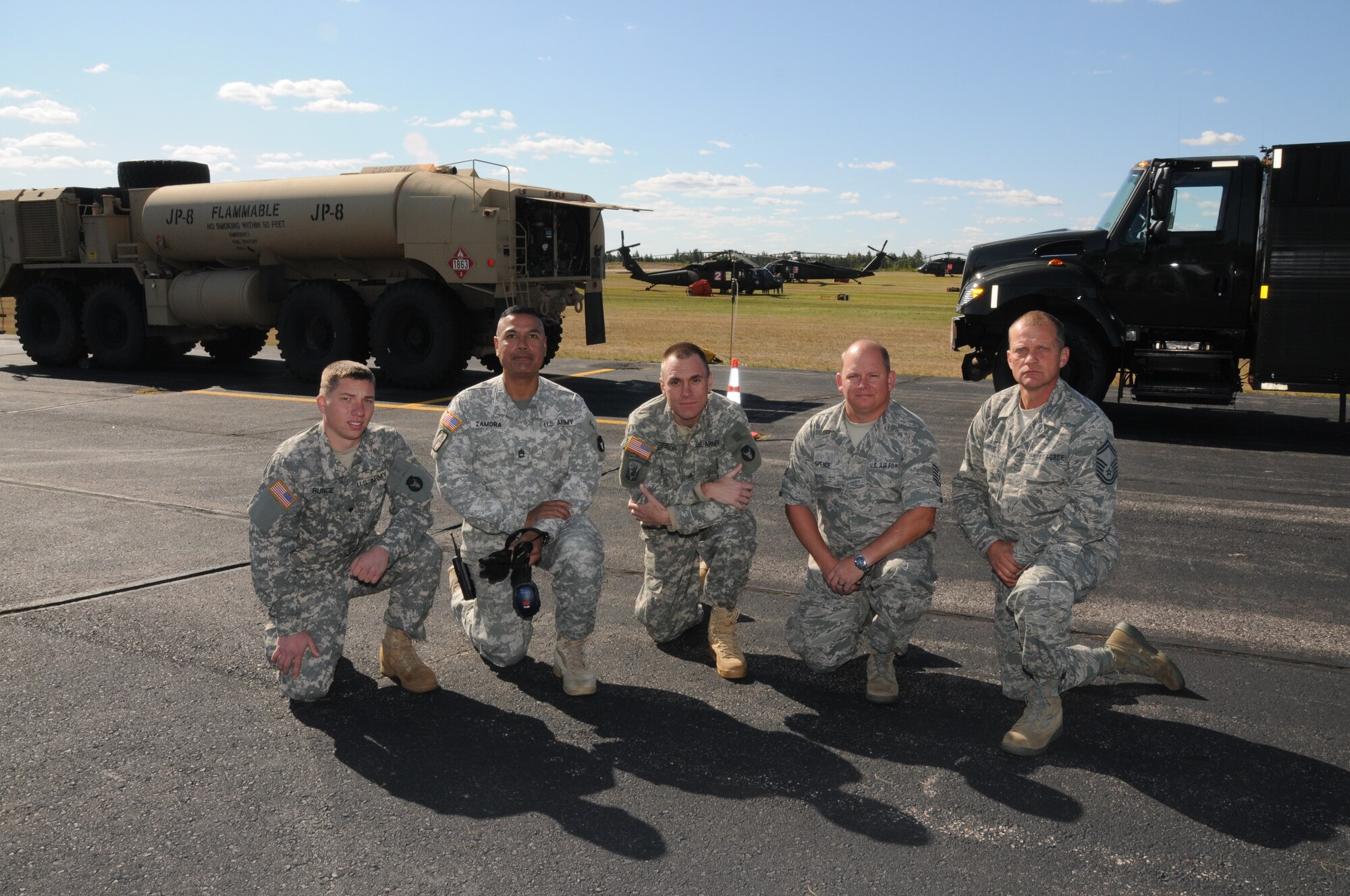 148th Fighter Wing members Senior Master Sgt. Ted Windus Jr., and Tech. Sgt. Harold Spence, pose with Army National Guard members Sgt. Nick Jefferson, Sgt. 1st Class Miguel Zamora, and Spc. Jacob Runge in front of an Army Heavy Expanded Mobility Tactical Truck (HEMTT) and an Air Force R-11 Refueler in Ely, Minn. Sept. 16, 2011.  The refueling trucks worked in tandem to keep the Blackhawk helicopters (shown in the background) in the air to dump 550 gallon loads of water on the fires in the Ely area.  (U.S. Air Force photo by Master Sgt. Ralph J. Kapustka.)