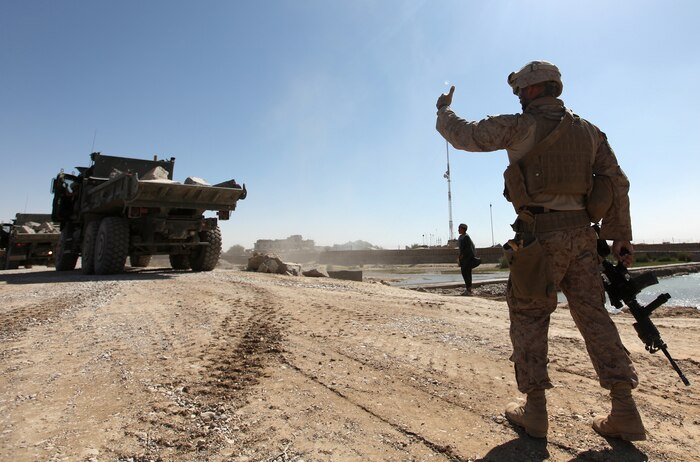 A Marine with 7th Engineer Support Battalion, 2nd Marine Logistics Group (Forward) guides a line of Medium Tactical Vehicle Replacement vehicles down a causeway into Helmand River near Forward Operating Base Sabit Qadam, Afghanistan, Sept. 27. For the last three weeks Marines with the battalion, along with other elements, have hauled tons of rubble to the site each day, which will serve as a base to launch a forthcoming bridge that will span the remainder of the river. (U.S. Marine Corps photo by Sgt. Justin J. Shemanski)
