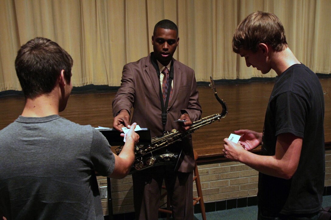 Gunnery Sgt. Jason Knuckles, 9th Marine Corps District Marine band placement director, hands out his business card to jazz enthusiasts Sean Haugen and Brett Kimble at Coon Rapids High School Sept. 27. Knuckles made several high school visits while traveling across Minnesota and Western Wisconsin to promote the Marine Corps Musician Enlistment Option Program. For additional imagery from their tour, visit www.facebook.com/rstwincities.