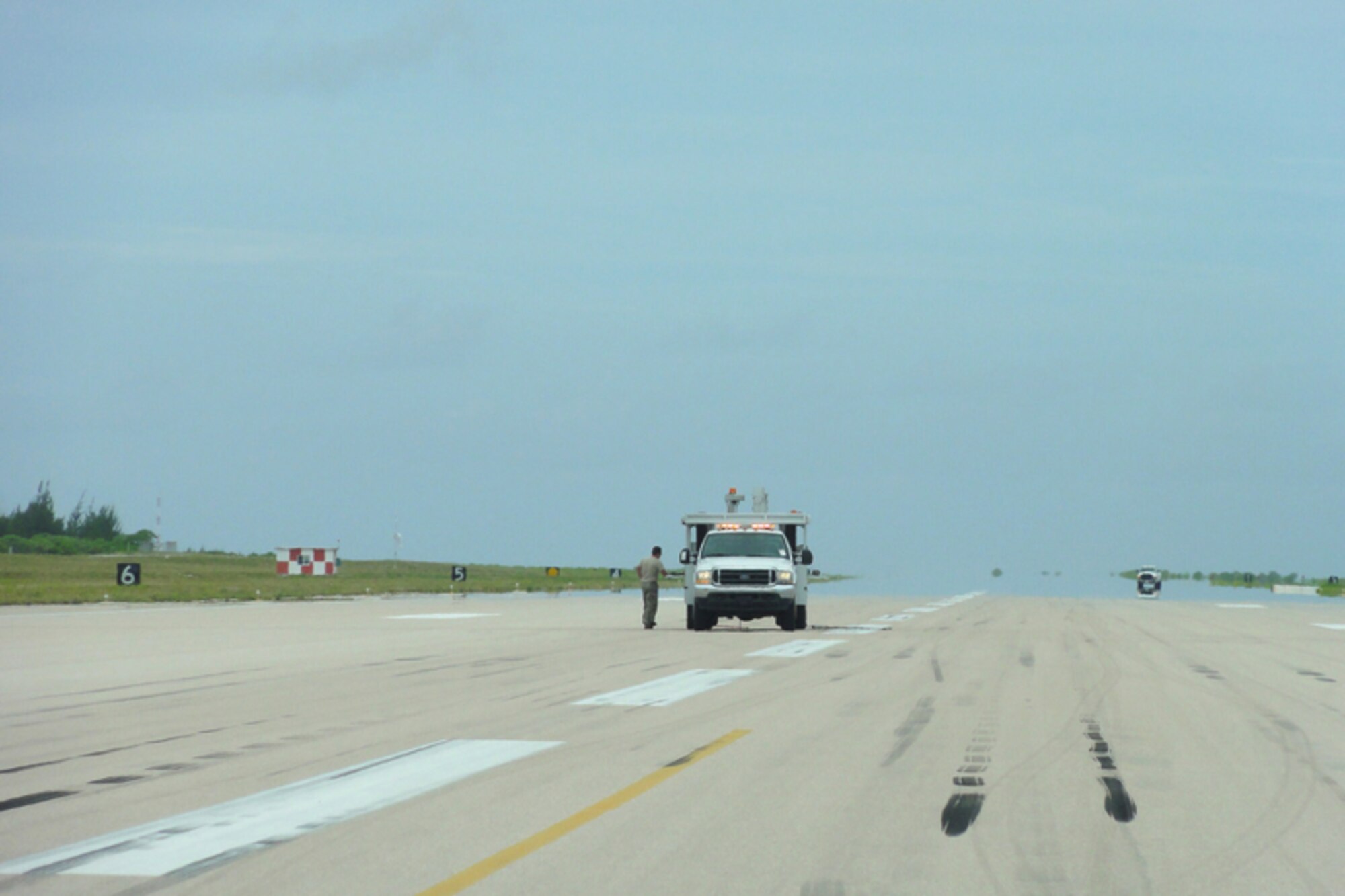 Tech. Sgt. Jeremy Morgan, AFCE SA Airfield Pavement Evaluation technician, stands next to a specialized pavement evaluation truck on the Wake Island runway.  It is the longest strategic runway in the Pacific Islands at nearly 10,000 feet. (U.S. Air Force photo/Capt Amy Hansen)