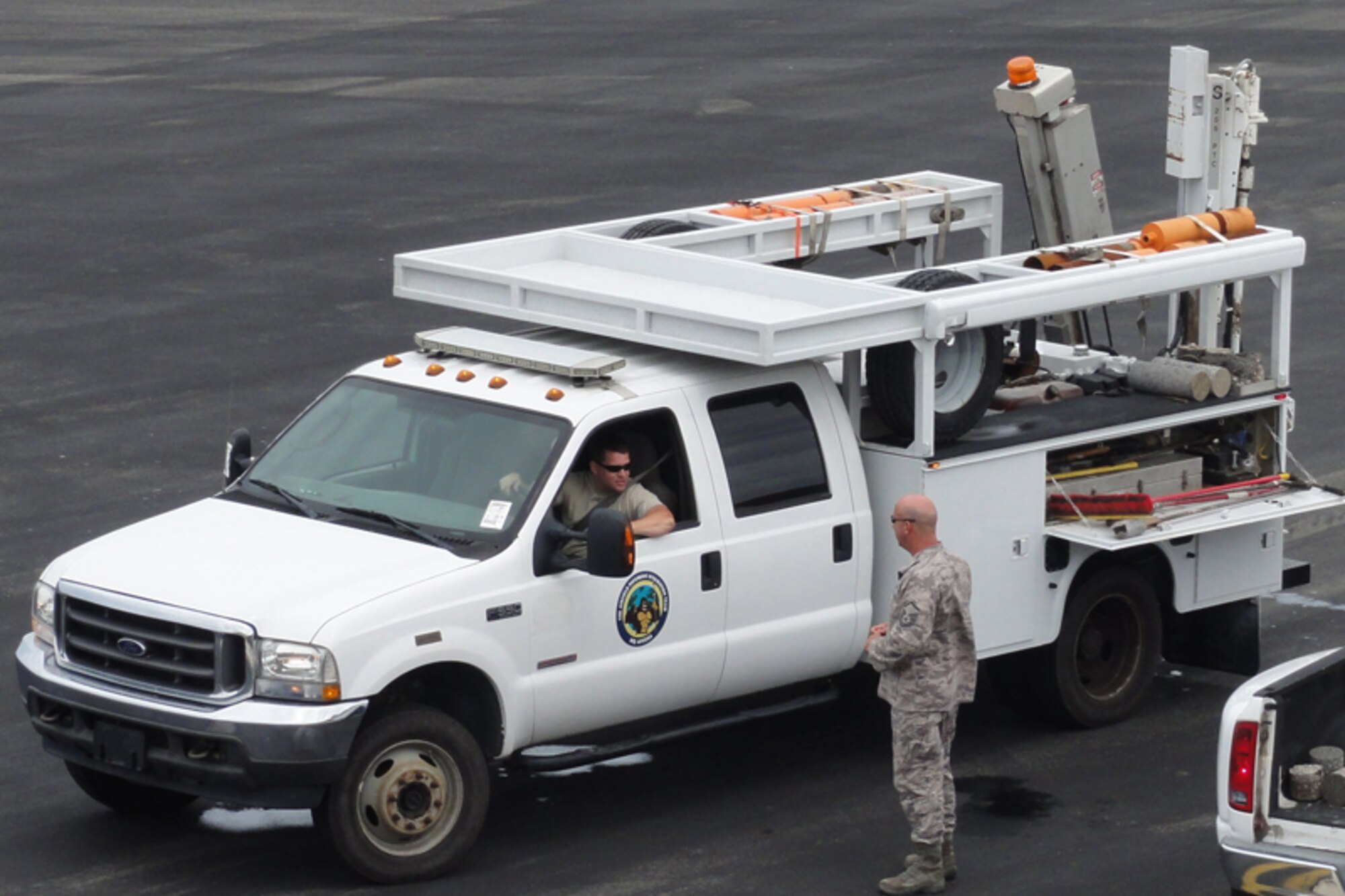 Tech. Sgt. Jeremy Morgan, Airfield Pavement Evaluation technician from the Air Force Civil Engineer Support Agency at Tyndall Air Force Base, Fla., talks with Master Sgt. Jean-Guy Fleury, 611th Detachment 1 infrastructure superintendent, from a specialized truck fitting with pavement testing equipment on the Wake Island Airfield flightline. (U.S. Air Force photo/Capt Amy Hansen)