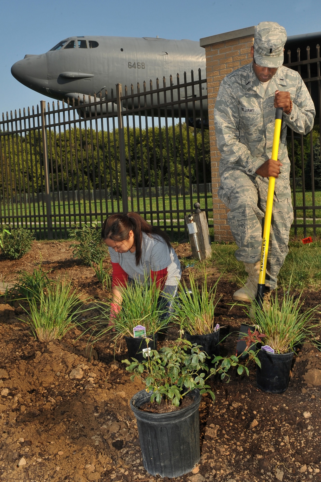 U.S. Air Force Tech. Sgt. Judith Guerra, U.S. Strategic Command, puts a plant in the ground while U.S Air Force 1st Lt. Rajeev Williams, with the 55th Medical Support Squadron, digs holes for plants during a beautification project at the Kenney Gate on Offutt Air Force Base, Neb., Aug. 31. Team Offutt members and the Bellevue Garden Club came together to place more than 400 plants as a part of the gate beautification project. (U.S. Air Force photo by Charles Haymond/Released)