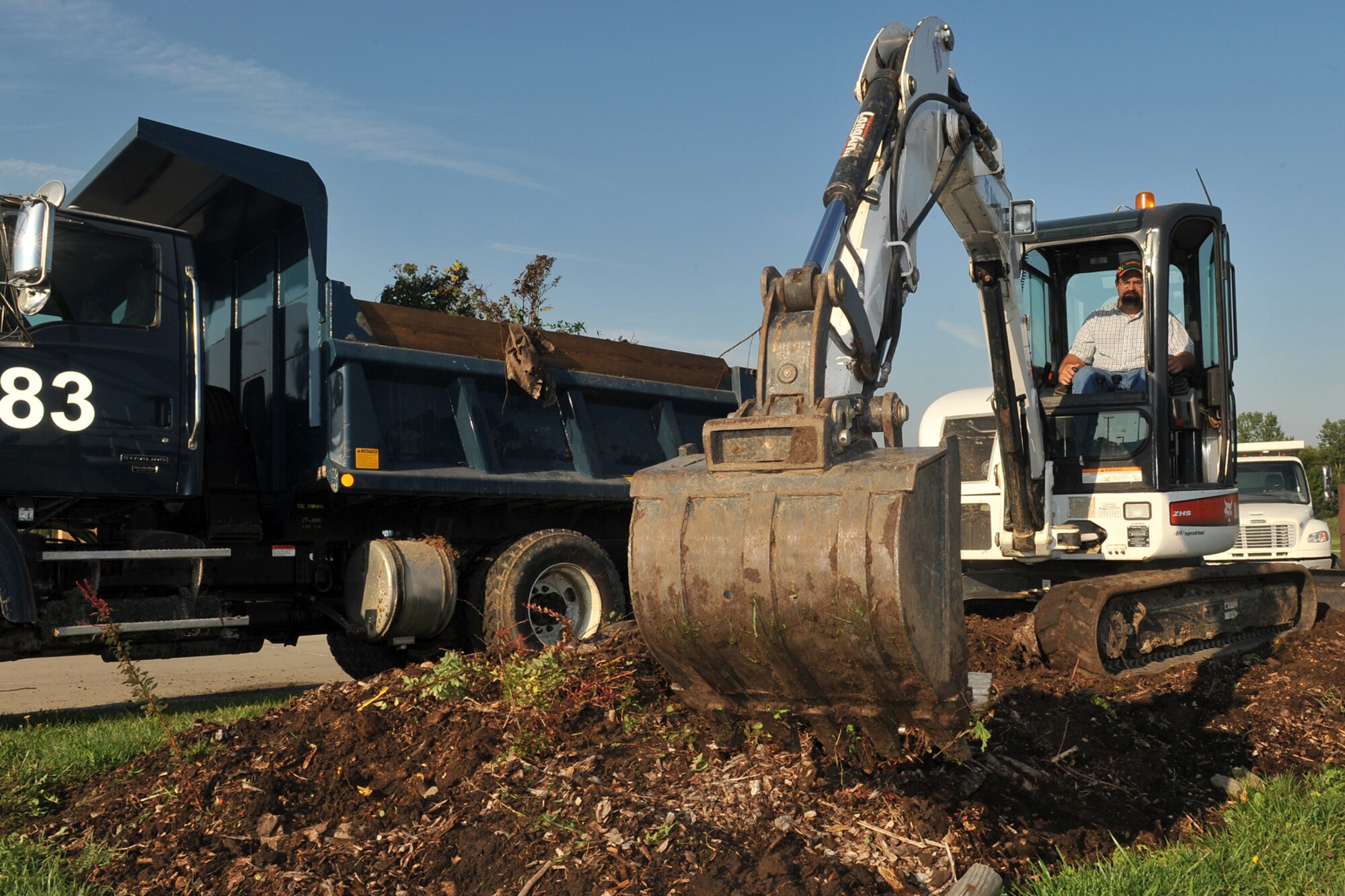 Larry Andreason, 55th Civil Engineering Squadron, uses a back-hoe to remove debris during a gate beautification project at the Kenney Gate on Offutt Air Force Base, Neb., Aug. 31. Civil engineering personnel started the beautification project by removing old planting materials and prepping the area for new plants. (U.S. Air Force photo by Charles Haymond/Released)