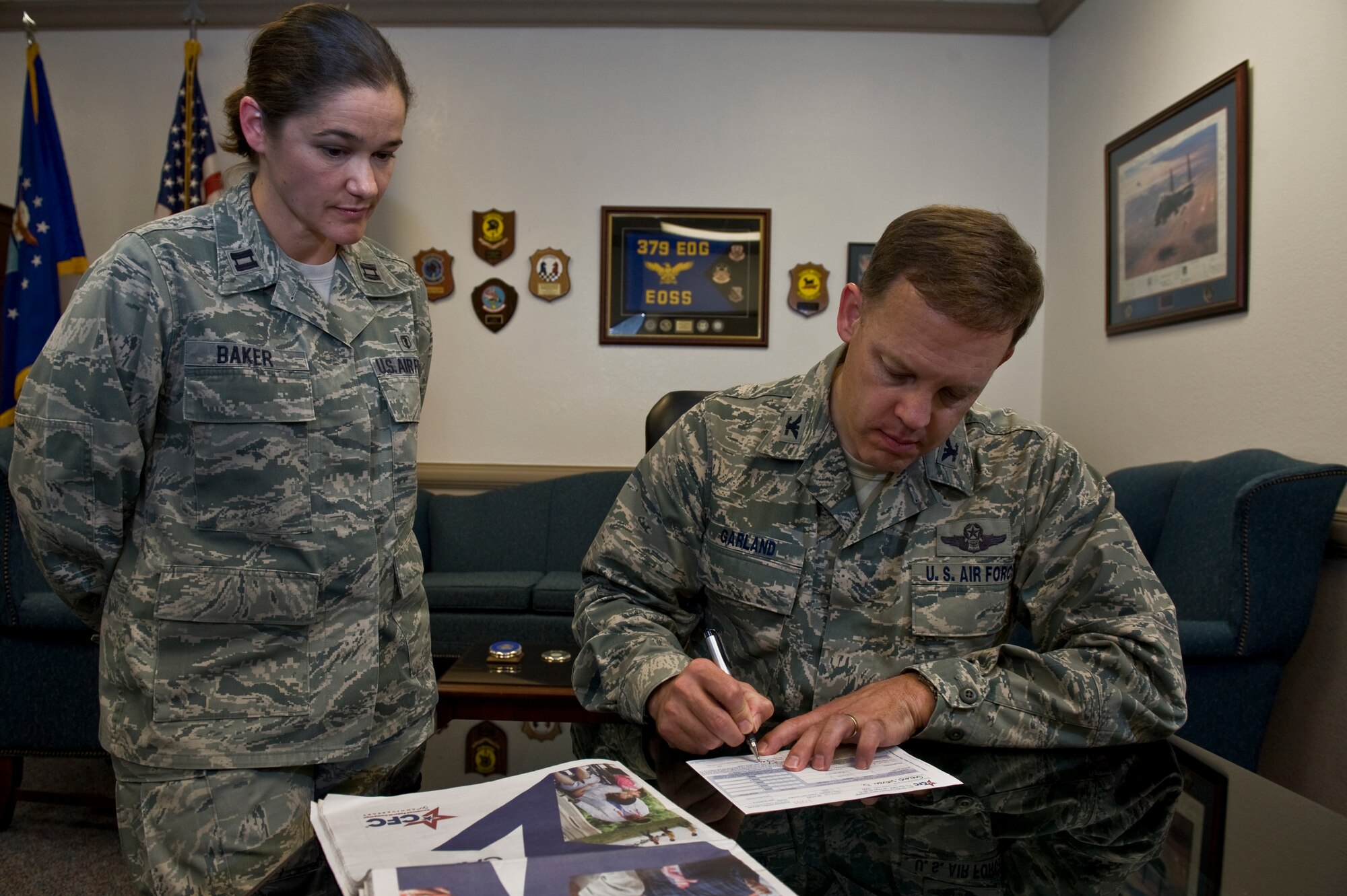 U.S. Air Force Col. Steven Garland, 99th Air Base Wing commander, signs his pledge to the Combined Federal Campaign while Capt. Tammy Baker, 99th Medical Surgical Specialties chief staff audiologist and Nellis CFC lead representative, watches Sept. 21, 2011, at Nellis Air Force Base, Nev. The CFC is one of two authorized Air Force campaigns that enables federal employees to make donations to a number of approved charitable organizations. (U.S. Air Force photo by Airman 1st Class Daniel Hughes/Released)

