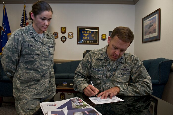 U.S. Air Force Col. Steven Garland, 99th Air Base Wing commander, signs his pledge to the Combined Federal Campaign while Capt. Tammy Baker, 99th Medical Surgical Specialties chief staff audiologist and Nellis CFC lead representative, watches Sept. 21, 2011, at Nellis Air Force Base, Nev. The CFC is one of two authorized Air Force campaigns that enables federal employees to make donations to a number of approved charitable organizations. (U.S. Air Force photo by Airman 1st Class Daniel Hughes/Released)

