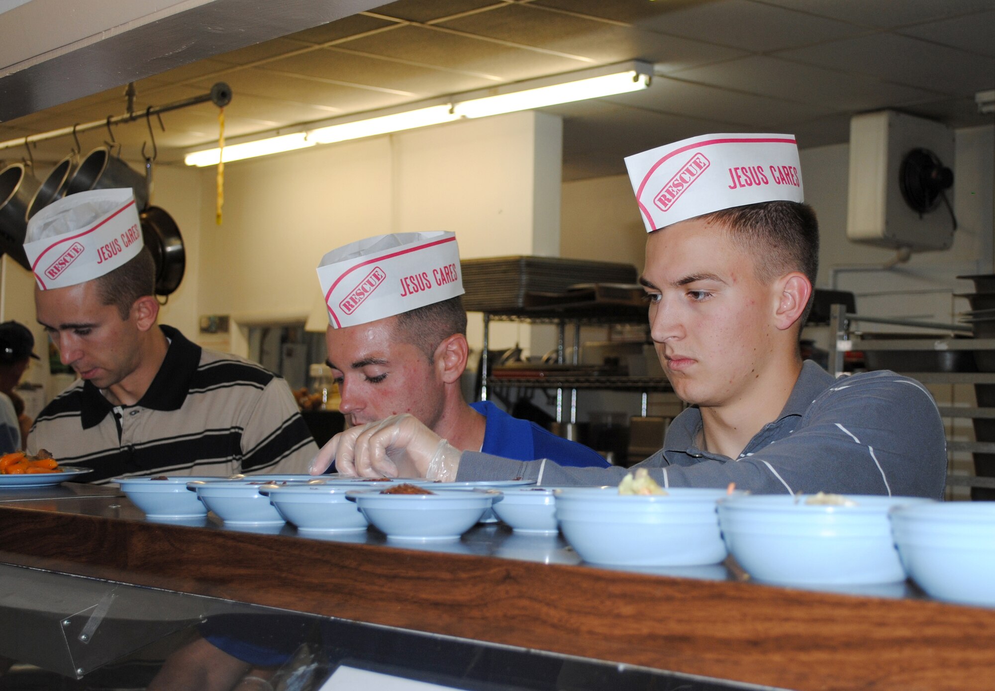 From left, Airmen 1st Class Kyle Murphy, 341st Forces Support Squadron food service apprentice; Jeremy Alexander, 341st Missile Maintence Squadron facilities maintenance support technician; and Tripp McCool, 341st MMXS electromechanical technician, prepare food for other volunteers to serve at the Great Falls Rescue Mission Sept. 14.  Their volunteer efforts were coordinated through the First Term Airmen's course mandatory for all inbound Airmen.  (U.S. Air Force photo/Airman 1st Class Katrina Heikkinen)