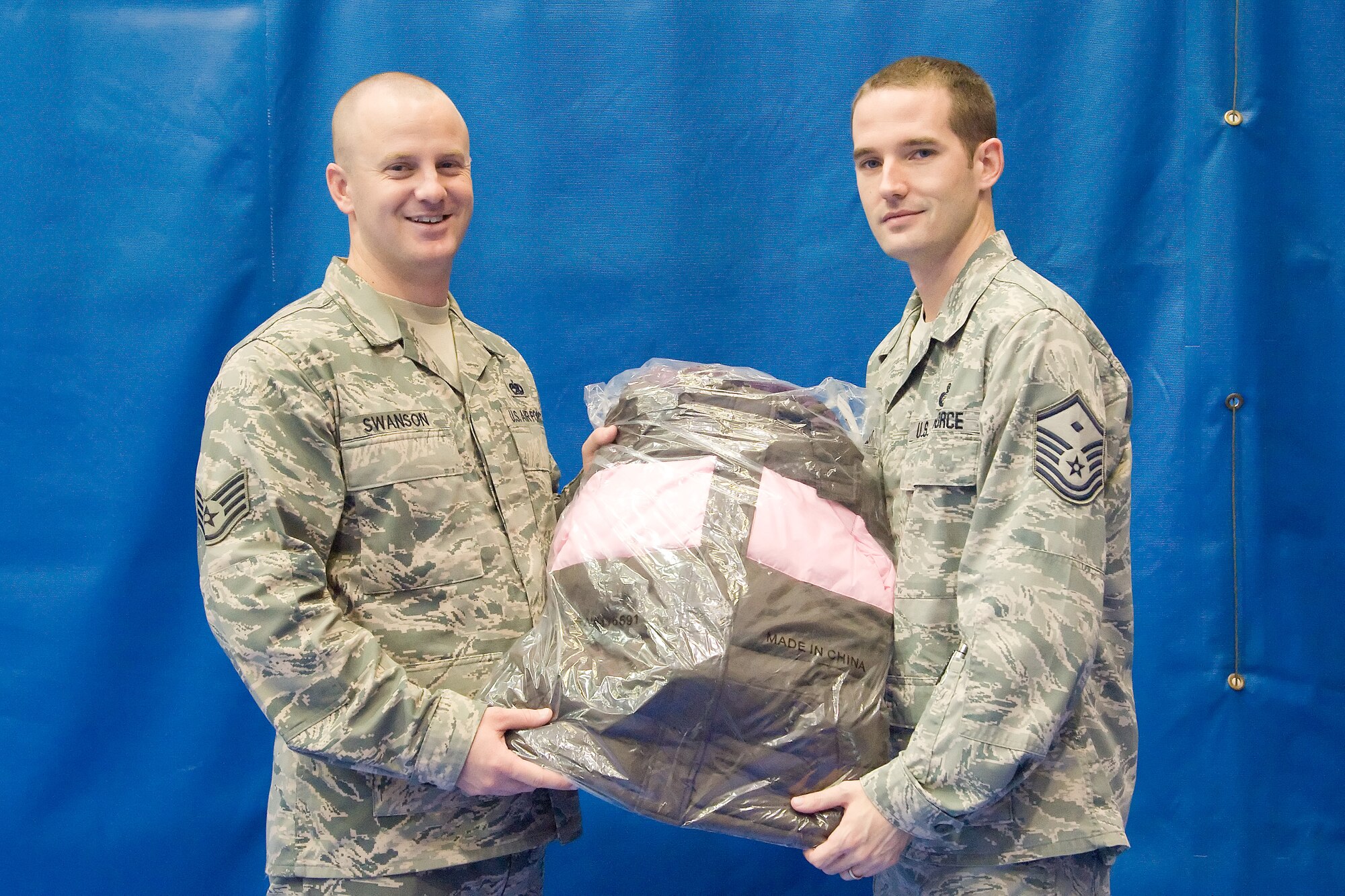 Staff Sgt. Eric Swanson (left), an honor guard member with the 436th Airlift Wing, gives a donated coat to Master Sgt. Jeff Gilbert, the first sergeant of the 9th Airlift Squadron, on behalf of Friends of Family Support Sept. 27, 2011, at Dover Air Force Base, Del. Friends of Family Support is a nonprofit organization made up of active duty, retirees, and their families, to improve the quality of life at Dover AFB. (U.S. Air Force photo by Adrian Rowan) 