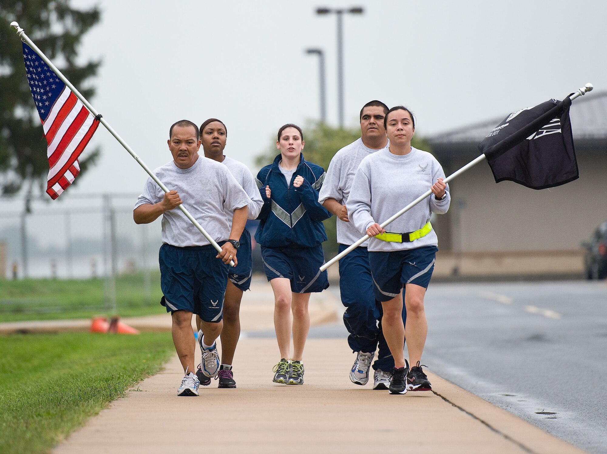 Team Dover members run with the American and Prisoner of War/Missing in Action flags during the POW/MIA run Sept. 23, 2011, at Dover Air Force Base, Del. Team Dover hosted the run and a vigil to commemorate American POWs and MIAs. (U.S. Air Force photo by Roland Balik)