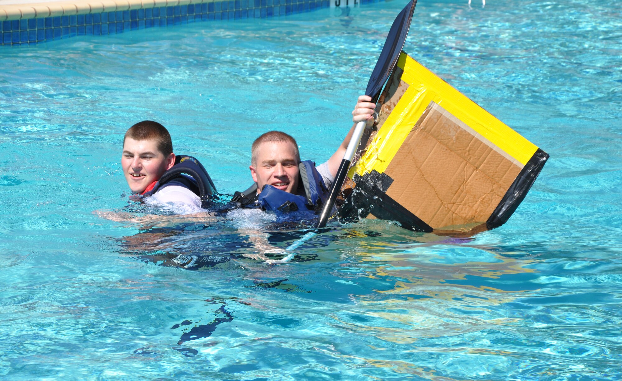 SAN ANGELO, Texas -- Despite sinking to the bottom from the start, Senior Airman Joshua Suter, 17th Communications Squadron, and Senior Airman Michael Wagner, 17th CS, never give up as they paddle and swim their up and down the Recreation Camp pool during the Build a Boat contest Sept. 24.  Team Iceburgs, Suter and Wagner, won The Best Design category. (U.S. Air Force photo/Connie Hempel)