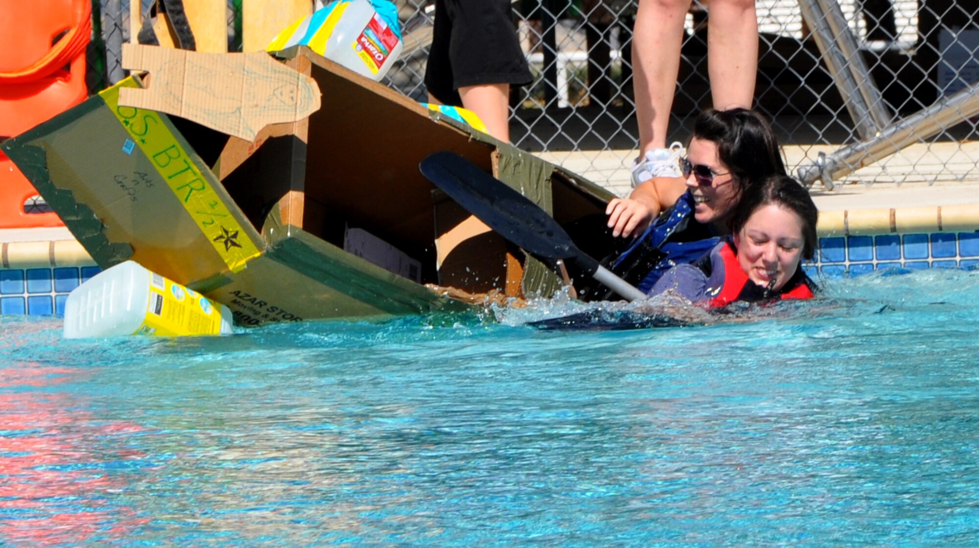 SAN ANGELO, Texas -- Betterhalves team members Christi Hedgepath (front) and Ashley Carroll (back) quickly sink just after launching their makeshift boat of cardboard boxes, duct tape and milk jugs into the Recreation Camp pool during the Build a Boat contest Sept. 24.  Team Betterhalves won The Titanic Award. (U.S. Air Force photo/Connie Hempel)