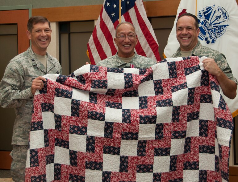 Army Master Sgt. Antonio Blas, Army liaison NCO in charge, Air Force Mortuary Affairs Operations, is presented a Quilt of Valor by Col. Thomas Joyce, commander, AFMAO, and Chief Master Sgt. David Fish, chief enlisted manager, AFMAO, at the Charles C. Carson Center for Mortuary Affairs, Dover Air Force Base, Del., Sept. 21, 2011. Blas served 32 years with the Army. (U.S. Air Force Photo/Staff Sgt. Agustin Salazar)