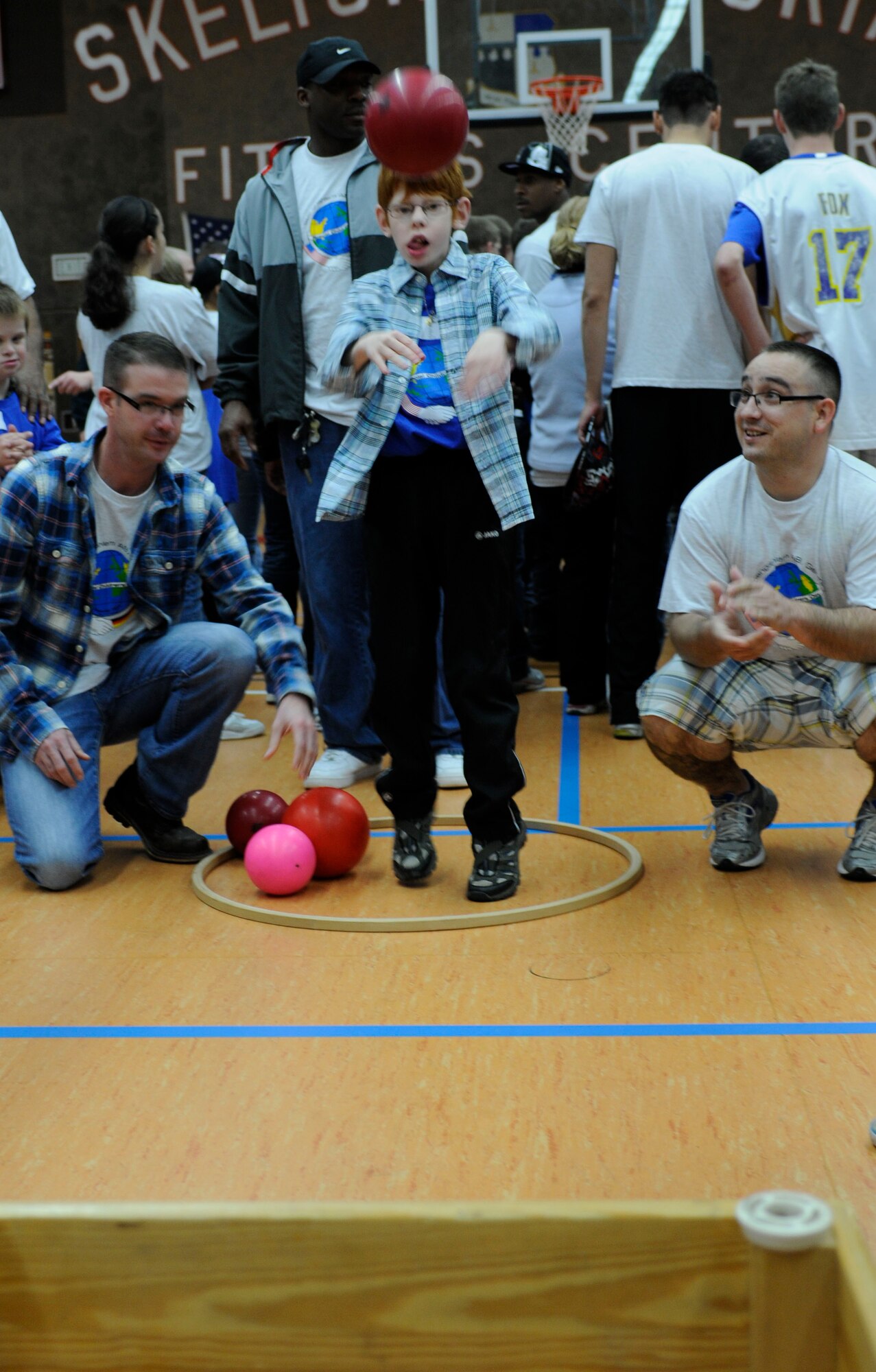 SPANGDAHLEM AIR BASE, Germany  --  Tech. Sgt. Jason Nipp, left, and Staff Sgt. Lance Ortiz, both from the 52nd Equipment Maintenance Squadron, watch as their buddy, Marc Gorgen, launches a ball into a bin during St. Martin’s Special Children’s Day here Sept. 22 at the Skelton Memorial Fitness Center. Airmen partnered up with children from Bitburg’s St. Martin’s School for a day of activities hosted by the air base. Airmen also volunteered to run the activities as children and their buddies went through them. This is the 16th year Spangdahlem AB has hosted the German and American partnership building event with the Bitburg school. (U.S. Air Force photo/Senior Airman Natasha E. Stannard)