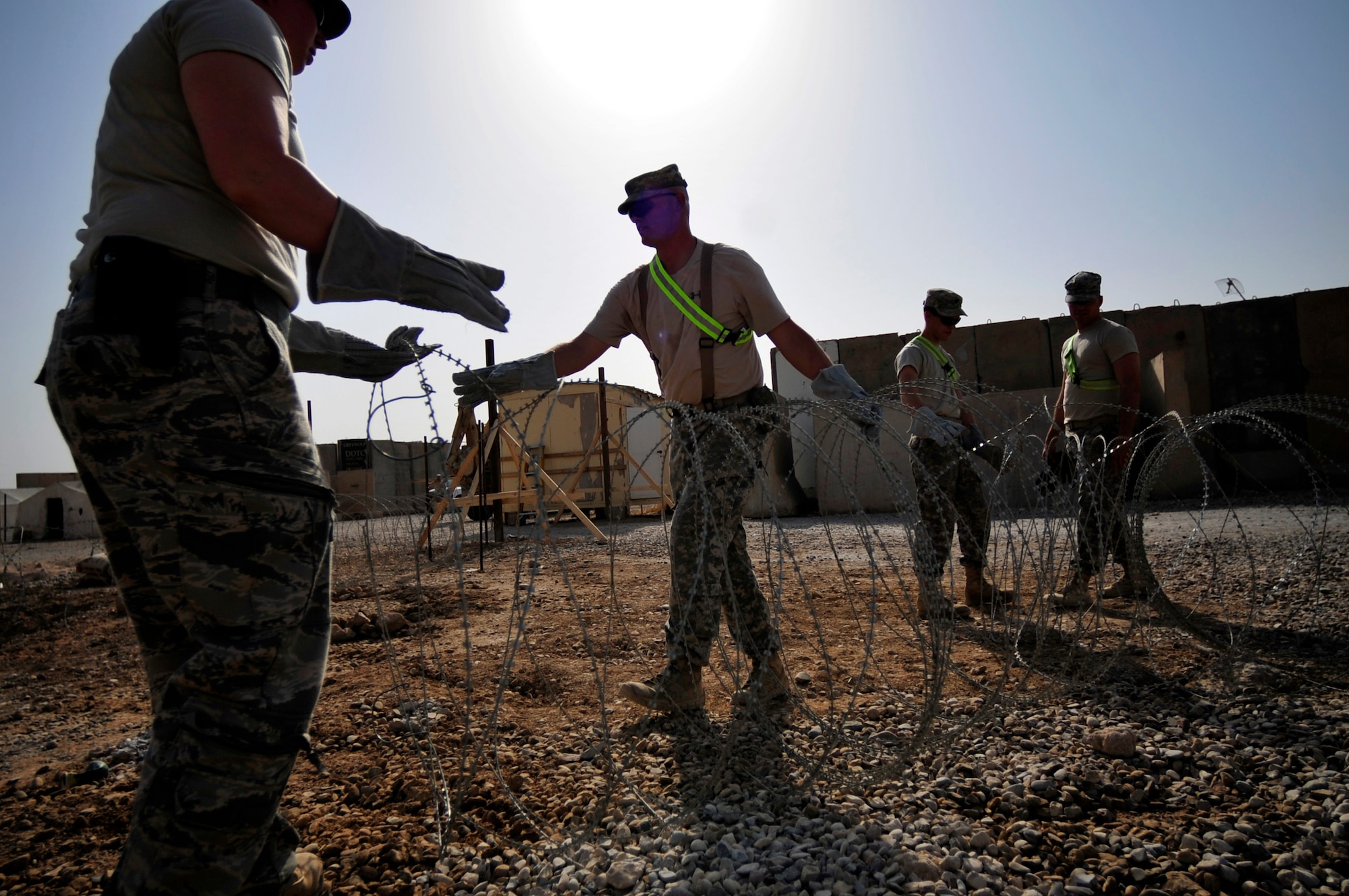 U.S. Air Force 1st Lt. Holly Bigelow, 467th Expeditionary Prime BEEF facility team engineer, left, Staff Sgt. Christopher Morian, middle, 389th Engineer Company electrician, and two soldiers, set up concertina wire to protect a refurbished building on Ali Base, Iraq, on Aug. 31, 2011. Bigelow is deployed from Vandenberg Air Force Base, Calif., and is from Barker, N.Y. Morian is deployed from Middletown Reserve Center Iowa, and is from Stockport, Iowa.  (U. S. Air Force photo/Master Sgt. Cecilio Ricardo)