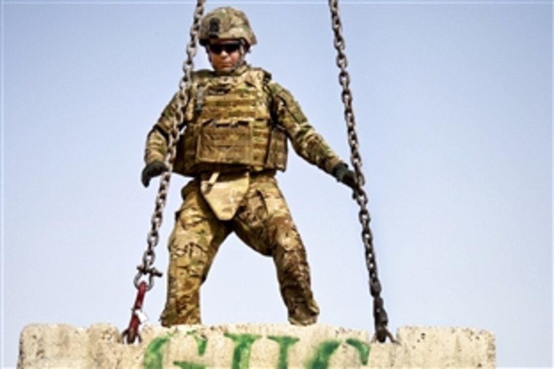 U.S. Army Spc. Dean Valbuena directs a crane moving Jersey barriers in Spin Boldak in Afghanistan's Kandahar province, Sept. 15, 2011. Valbuena is assigned to the 509th Forward Support Company, 504th Battlefield Surveillance Brigade.