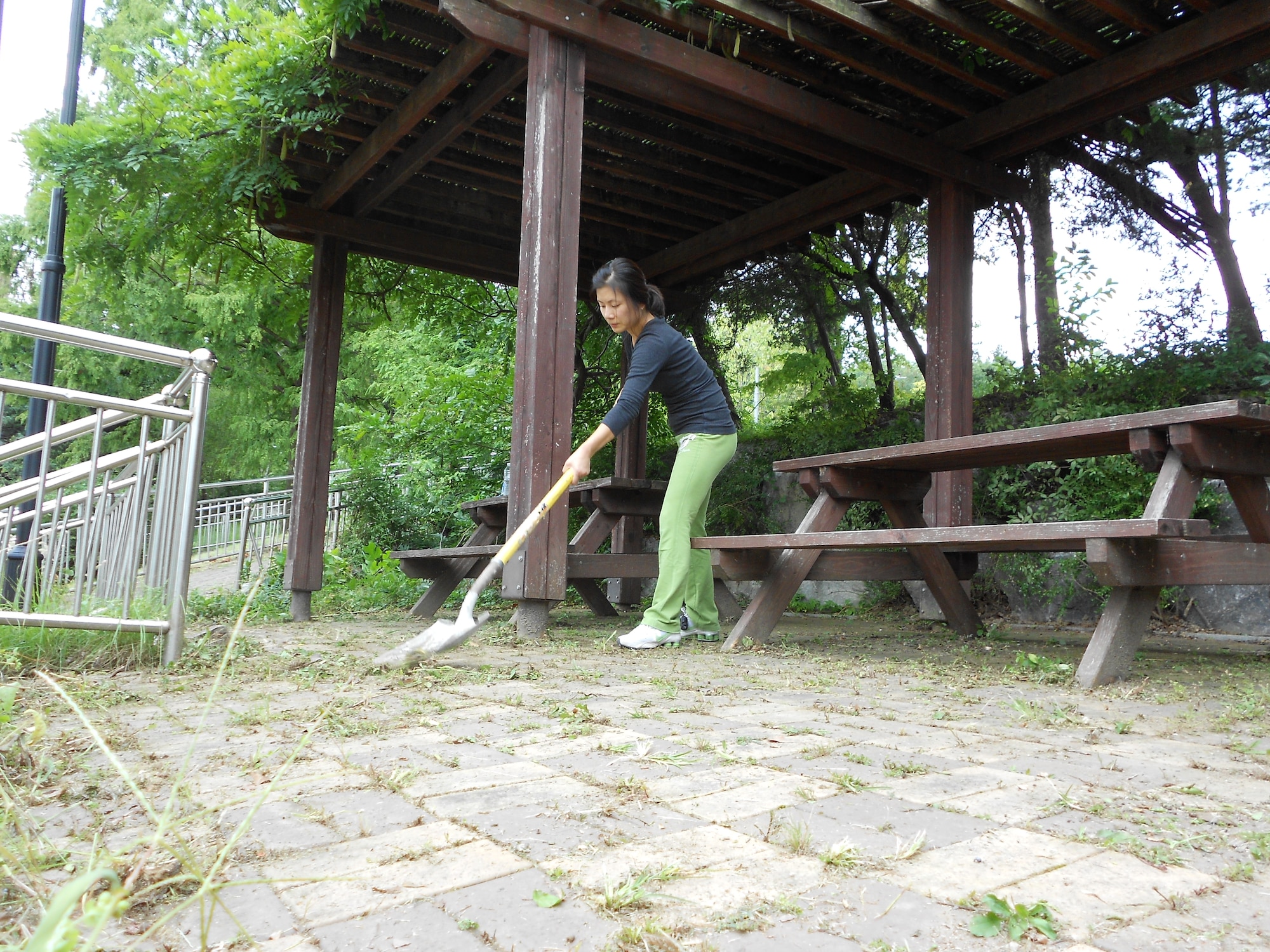 Okyong Yi, wife of Lt. Col. Roland Secody, removes plants growing between pavers Sept. 18, 2011 on the Mustang Valley Village playground. This self-help effort was the first clean up of the property since the residences of MVV were demolished Aug. 10. Residents of Hallasan Tower trimmed trees and plants, washed playground equipment, and swept the entire park. Currently, there is no start date for the Mustang Valley Village playground renovation. It was discussed during a recent Facilities Management Board and there should be movement on the project once it gets approved. (U.S. Air Force photo/Senior Master Sgt. Stuart Camp)