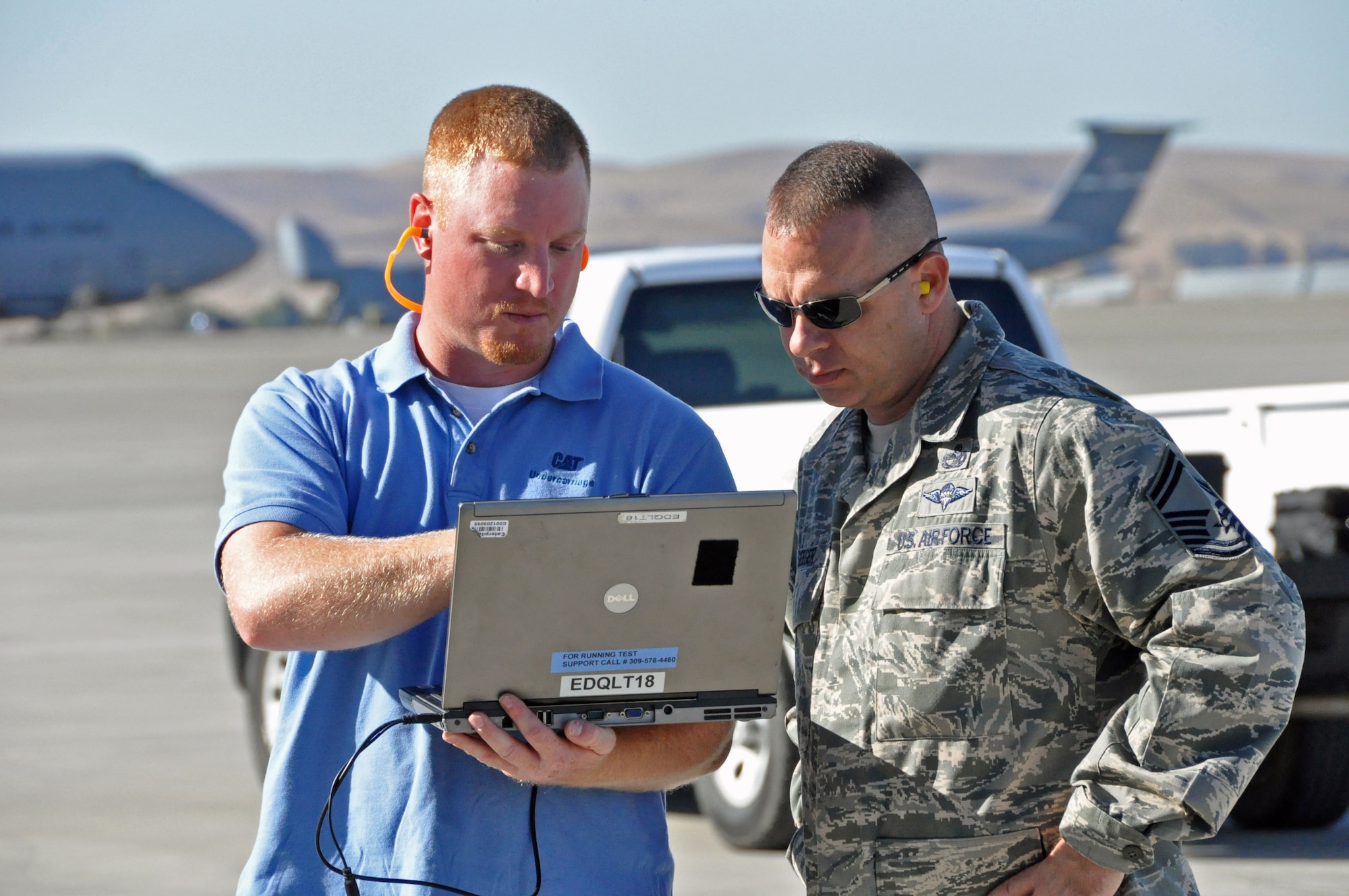 Eric Woods, Caterpillar engineer, shows Senior Master Sgt. Greg Seeger, Air Mobility Command Headquarters air transportation command policy manager, a laptop that displays the readings of the stress tests on the forklift Sep. 21 on the flightline at Travis. (U.S. Air Force photo/ Staff Sgt. Patrick Harrower)