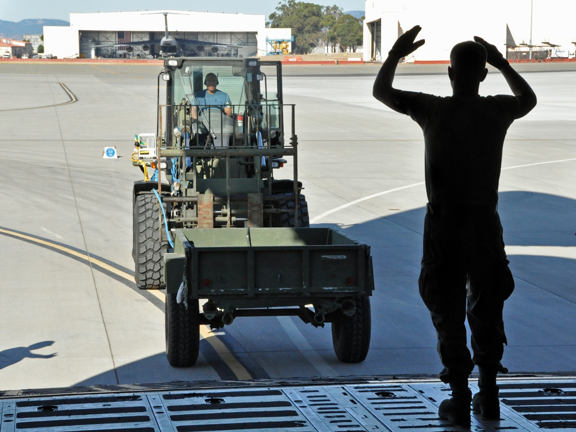 Staff Sgt. Christopher Messer, 60th Aerial Port Squadron aerial porter, marshals a forklift as it pushes a trailer up the cargo ramp of a C-5 Galaxy Sep. 21 on the flightline at Travis. (U.S. Air Force photo/ Staff Sgt. Patrick Harrower)