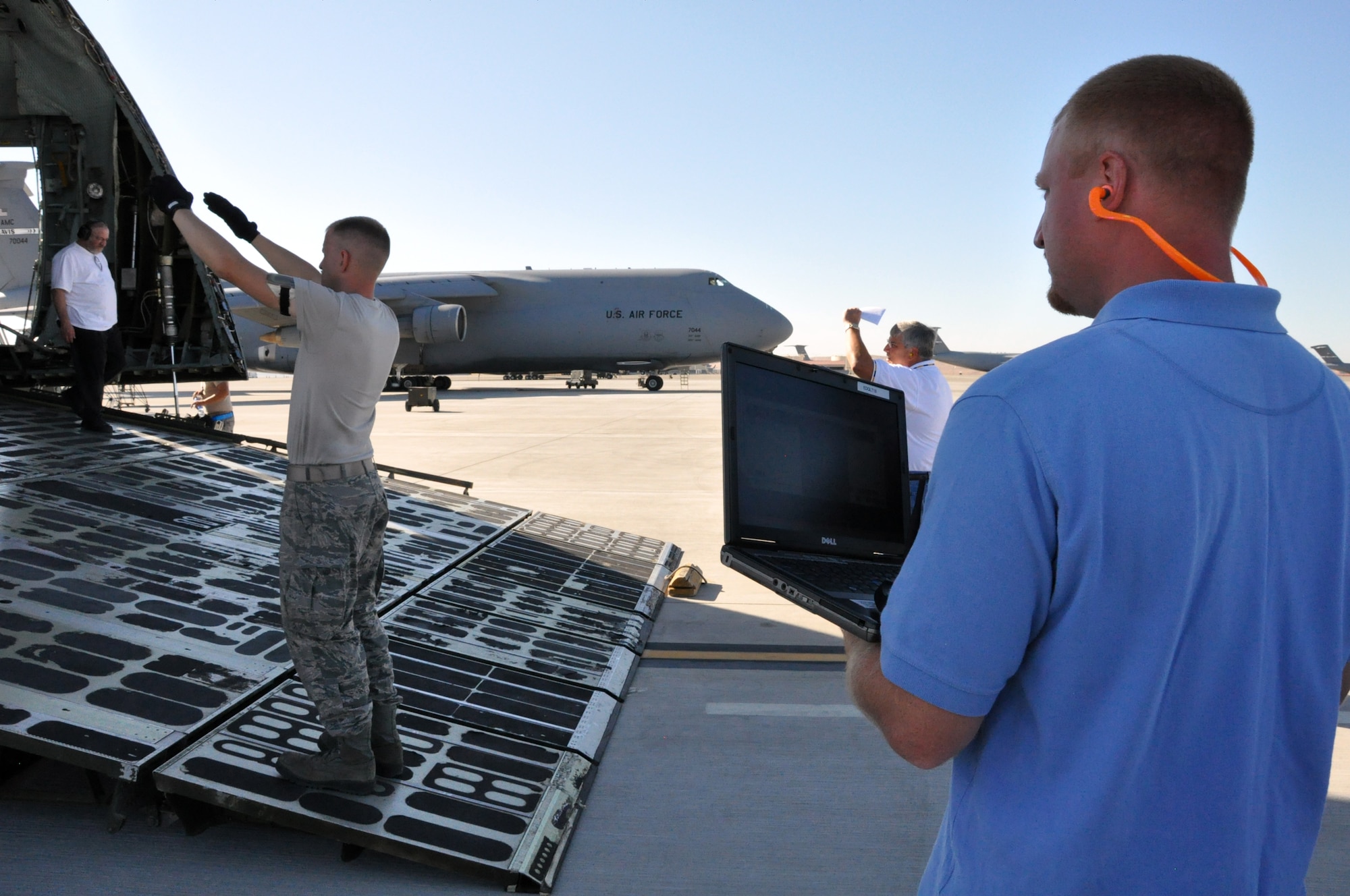 Staff Sgt. Christopher Messer, 60th Aerial Port Squadron aerial porter, marshals a forklift as it backs down the cargo ramp of a C-5 while Eric Woods, Caterpillar engineer, watches the laptop that displays the readings of the stress test on the forklift Sep. 21 on the flightline at Travis. (U.S. Air Force photo/ Staff Sgt. Timothy Boyer)