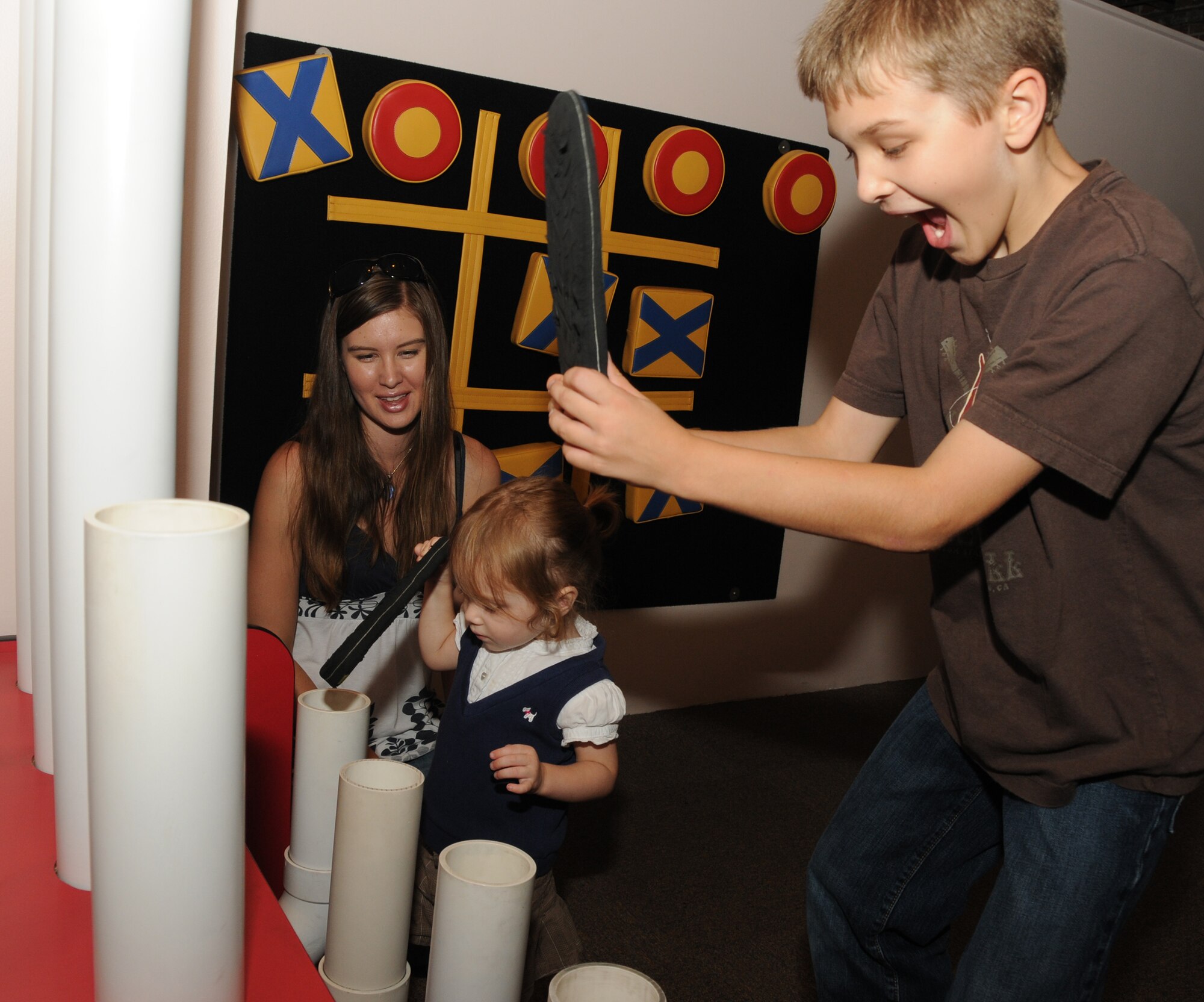 From left, Anna Ecklund watches her children, Natalie, 1, and Jeremy, 10, make music with pipes of various sizes during an outreach program at Lynn Meadows Discovery Center, Gulfport Sept. 24.  The children's dad is Staff Sgt. Adam Eklund, Keesler Marine Corps Detachment. The fun day was sponsored by the airman and family readiness center’s exceptional family member program and Child Find to help families connect with available community and base resources.  (U.S. Air Force photo by Kemberly Groue)