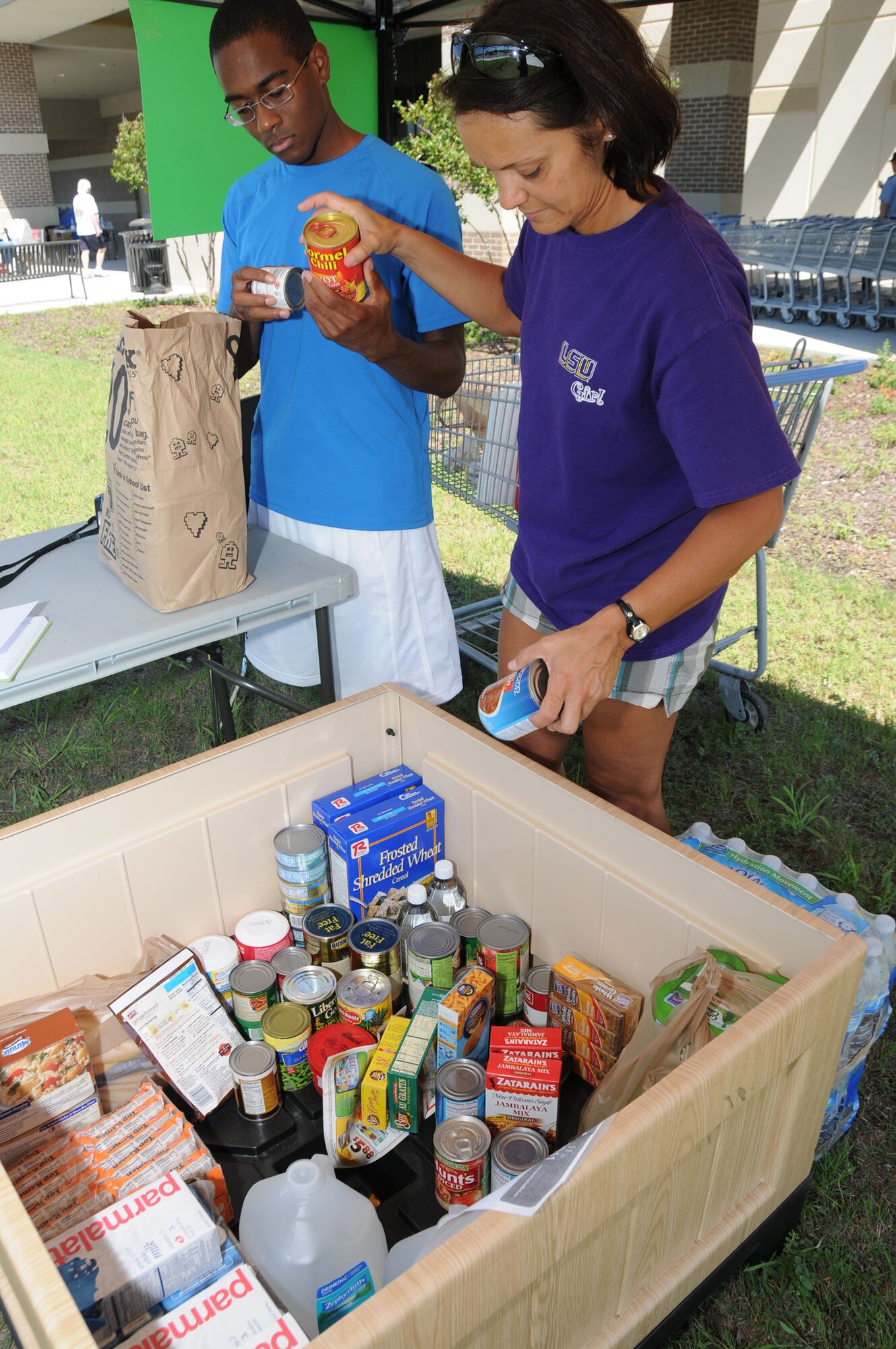 Airman 1st Class Michael Phipps, 81st Dental Squadron, and Tech. Sgt. Amanda Fisk, 81st Inpatient Operations Squadron, collect food for the Feds Feed Families drive at the commissary Aug. 15.  Fisk, who chaired Keesler's participation in the federal drive, said that the base donated 3,780 pounds of food which was donated to Loaves and Fishes soup kitchen in Biloxi, Fisher House, and the Gulf Coast Women’s Center for Nonviolence.  Figures released by the U.S. Office of Personnel Management this week reported that the Department of Defense led 40 government agencies, donating 2,004,613 pounds of a total 5,793,446 pounds of nonperishable food items to feed children, senior citizens and families in this year's drive.  By comparison, last year federal employees donated 1.7 million pounds of food.  (U.S. Air Force photo by Kemberly Groue)