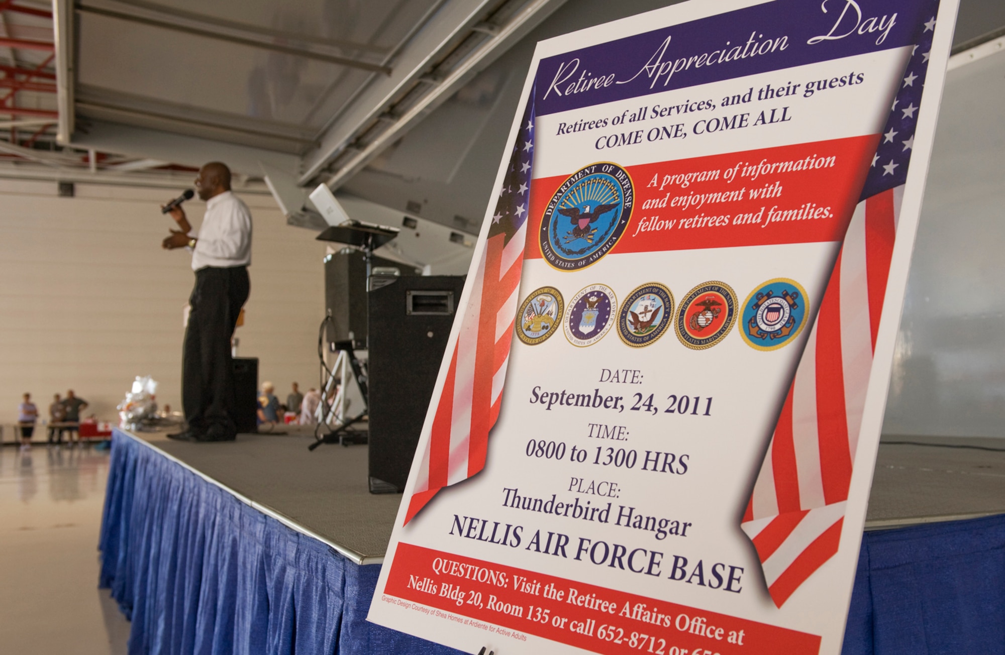 A Retiree Appreciation Day sign stands to the right of the stage where Leon Gilliam performs during the Nellis, Creech and the Nevada Test and Training Range Retiree Appreciation Day Sept. 24, 2011, at Nellis Air Force Base, Nev. More than 800 retirees were offered health screenings and enjoyed demonstrations, entertainment, door prizes and lunch at the Thunderbird hangar. (U.S Air Force photo by Senior Airman Stephanie Rubi/Released)