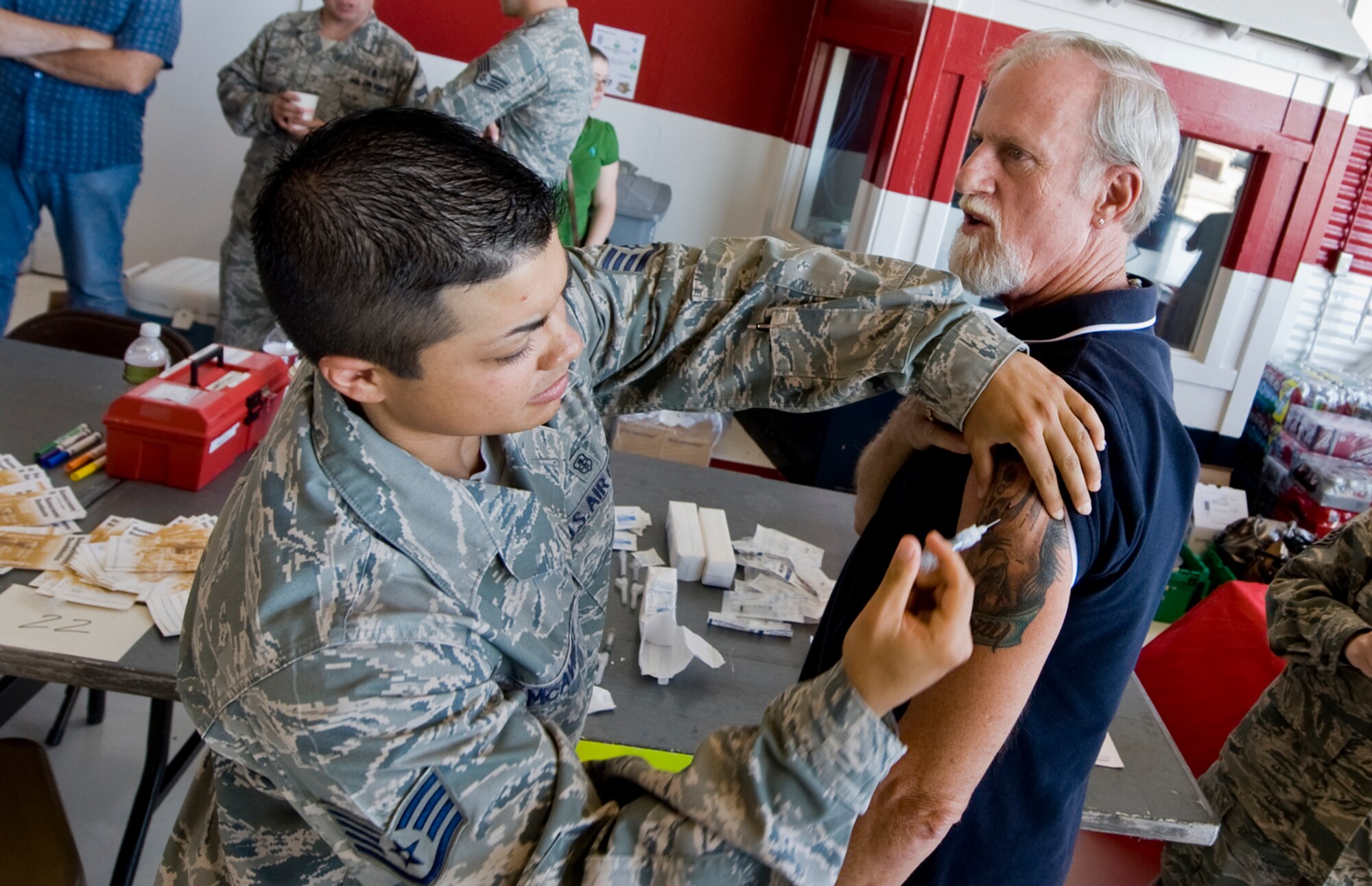 U.S. Air Force Staff Sgt. Kayleigh McAviney, 99th Medical Operations Squadron medical technician, administers a flu shot for retired U.S. Air Force Capt. Ray Goss during the Nellis, Creech and the Nevada Test and Training Range Retiree Appreciation Day Sept. 24, 2011, at Nellis Air Force Base, Nev. More than 800 attendees received health screenings throughout the day at the Thunderbird hangar.  (U.S Air Force photo by Senior Airman Stephanie Rubi/Released)