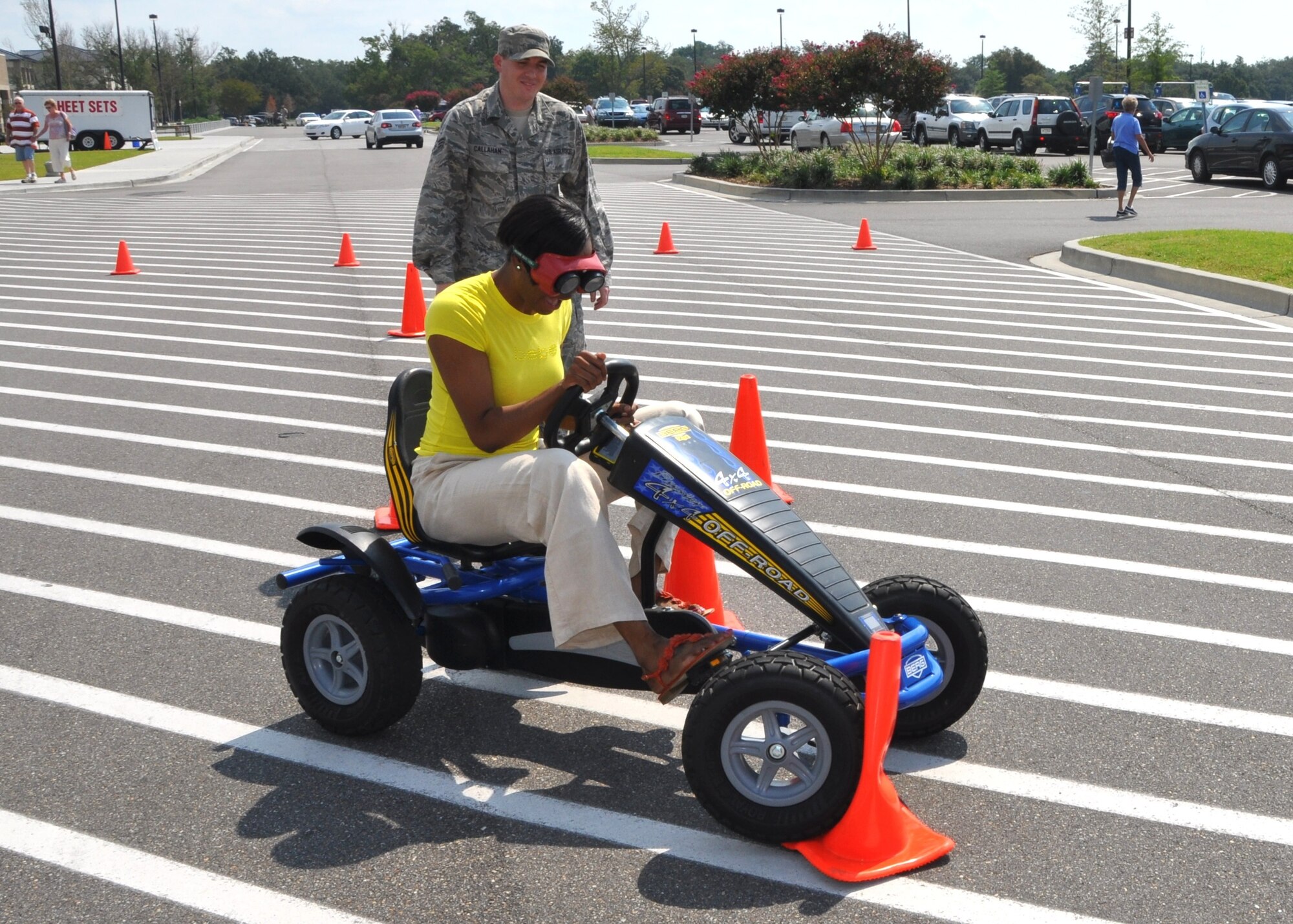 Senior Airman Dudley Callahan, 81st Medical Operations Squadron, helps Staff Sgt. Adrienne Russell-George, 81st Force Support Squadron, maneuver through the traffic cones set up to simulate obstacles on the “drunk goggles” course.  (U.S. Air Force photo by Steve Pivnick)