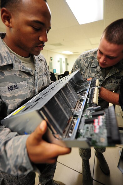 Airmen 1st Class Thomas Neal and Christopher Law, 4th Communications Squadron network operations technicians, work to add memory to a server in the Network Control Center (NCC) on Seymour Johnson Air Force Base, N.C., Sept. 27, 2011. The NCC is responsible for deleting computers from the network, rebooting servers, pushing updates and serves as a liaison between the base and the Integrated Network Operations and Security Center out of Langley AFB, Va. Neal is a native of Roxie, Miss., and Law hails from Atlanta.(U.S. Air Force photo by Senior Airman Rae Perry)