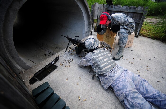 Senior Airman Josh Lien instructs a student firing the M-249 automatic machine gun Aug 31 at Joint Base Charleston-Air Base, during a Combat Arms Training and Maintenance qualifying course.  CATM courses consist of small arms training for the M-9 Beretta side arm, M-4 carbine rifle and heavy machine guns, such as the M-240 and M-249 automatic rifles. All Airmen are required to complete qualification courses annually or before deployments. Lien is a combat arms instructor from the 628th Security Forces Squadron, Combat Arms Section. (U.S. Air Force photo/Airman 1st Class Matthew Bruch)
