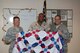 Col. Thomas Joyce, Air Force Mortuary Affairs Operations commander, presents Religious Program Spc. 2nd Class Timothy Owen, a Quilt of Valor at the end of his deployment at AFMAO, Dover Air Force Base, Del., Sept. 28, 2011. The Quilts of Valor Foundation provides hand-made quilts to servicemembers and veterans touched by war. (U.S. Air Force photo/Tech Sgt. Marvin B. Moore)