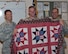 Col. Thomas Joyce, Air Force Mortuary Affairs Operations commander, presents Cpl. Matthew Duerr, Marine Corps liaison, a Quilt of Valor at the end of his deployment at AFMAO, Dover Air Force Base, Del., Sept. 28, 2011. The Quilts of Valor Foundation provides hand-made quilts to servicemembers and veterans touched by war. (U.S. Air Force photo/Tech. Sgt. Marvin B. Moore)